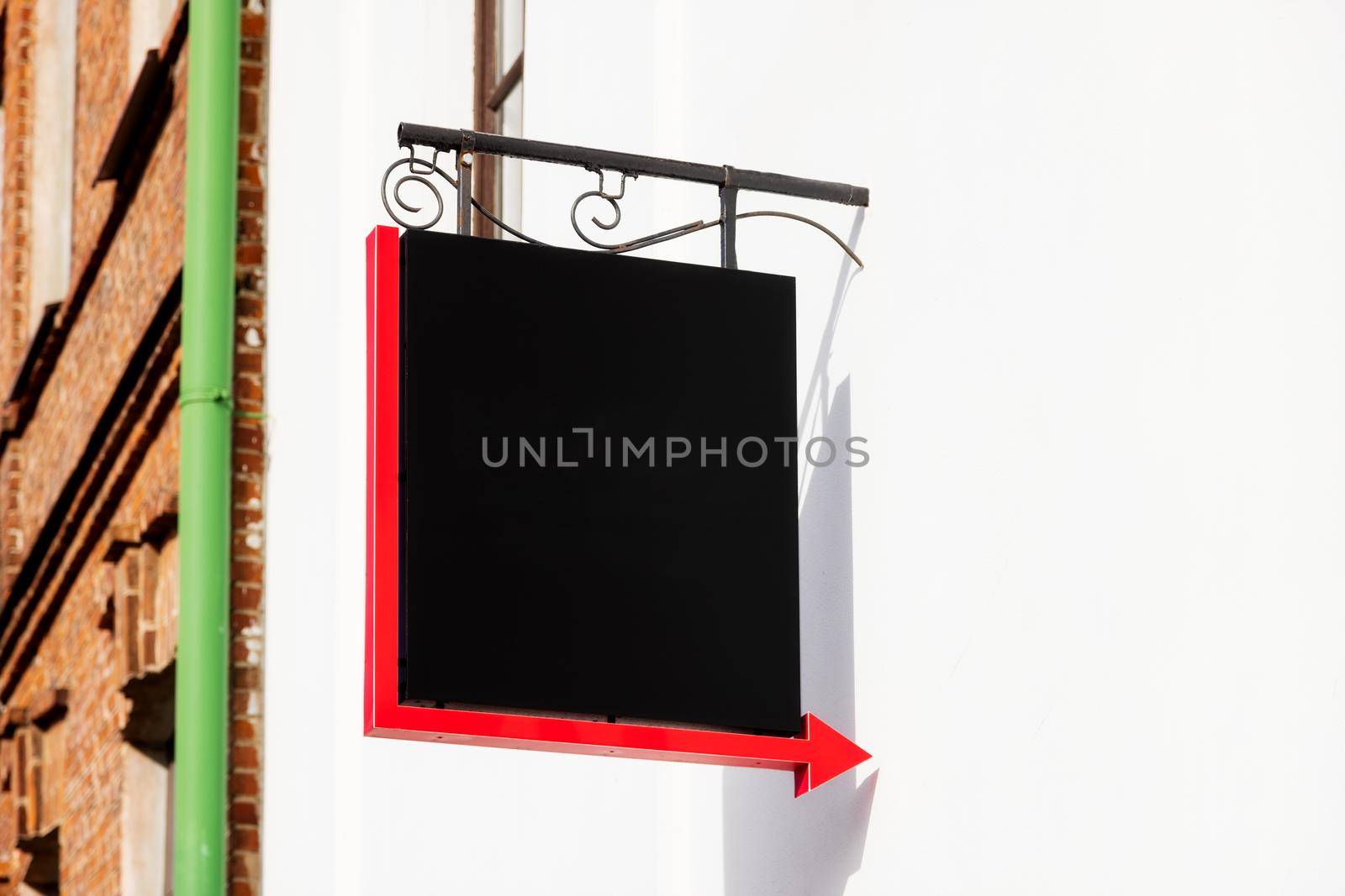 Mockup, large square sign on the wall, close-up. Black, empty blank sign with a red arrow on a white wall. space for logo, name of cafe, hotel, business and other object