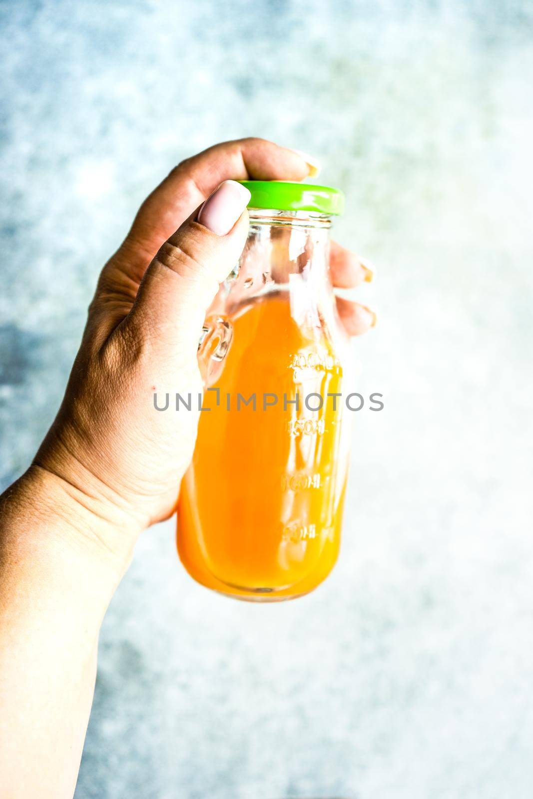 Woman hand holds homemade juice in the bottle