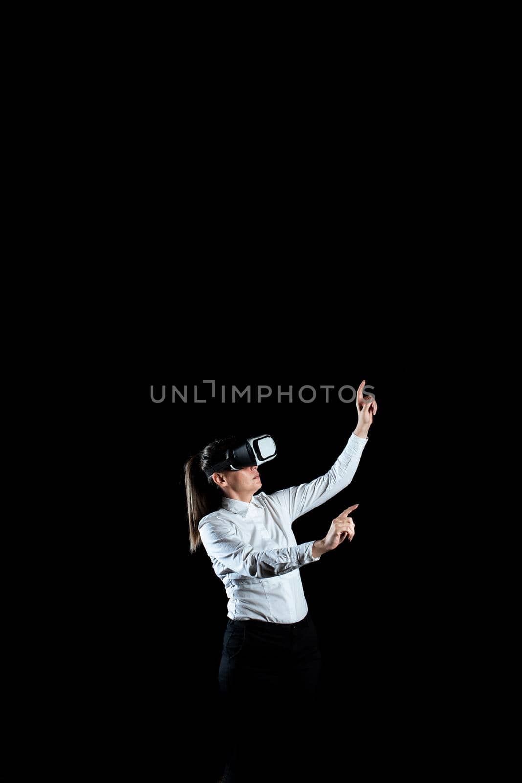 Businesswoman Wearing Virtual Reality Headset And Gesturing While Taking Professional Training. Woman Wearing Futuristic Simulator And Presenting Modern Technology. by nialowwa
