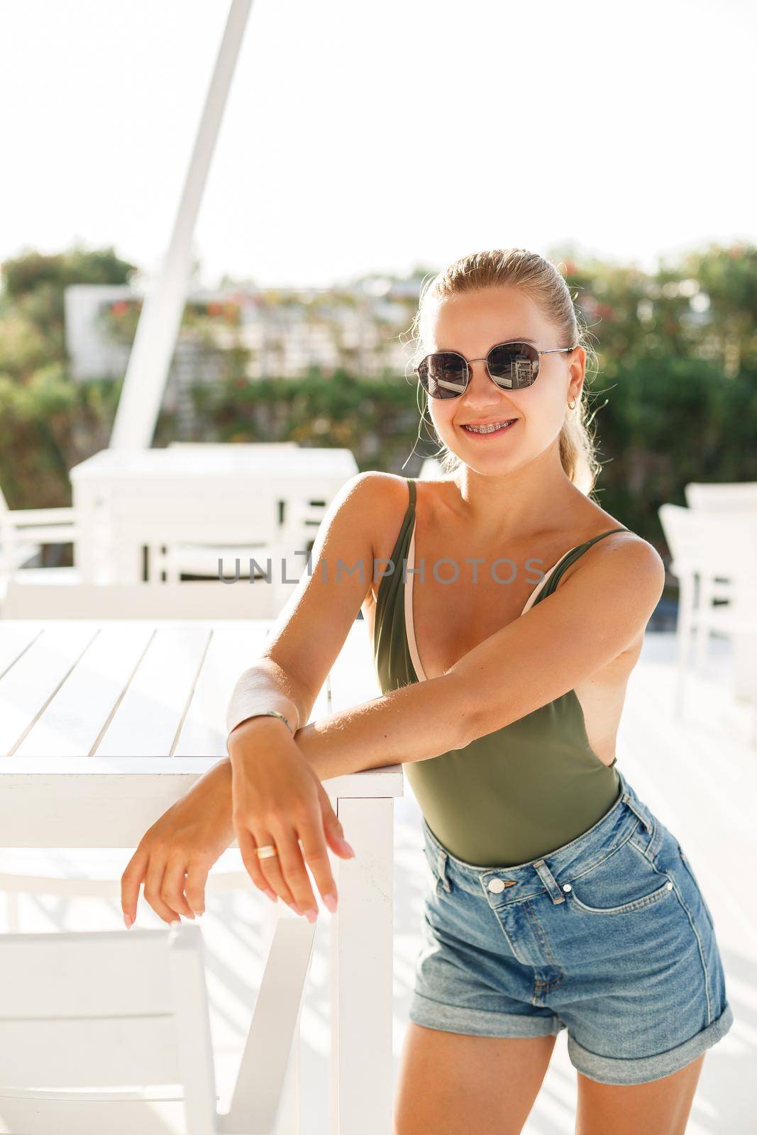Blond woman beautiful face tanned skin dressed in green top and denim shorts fashion clothing style summer clothes collection, summer and leisure