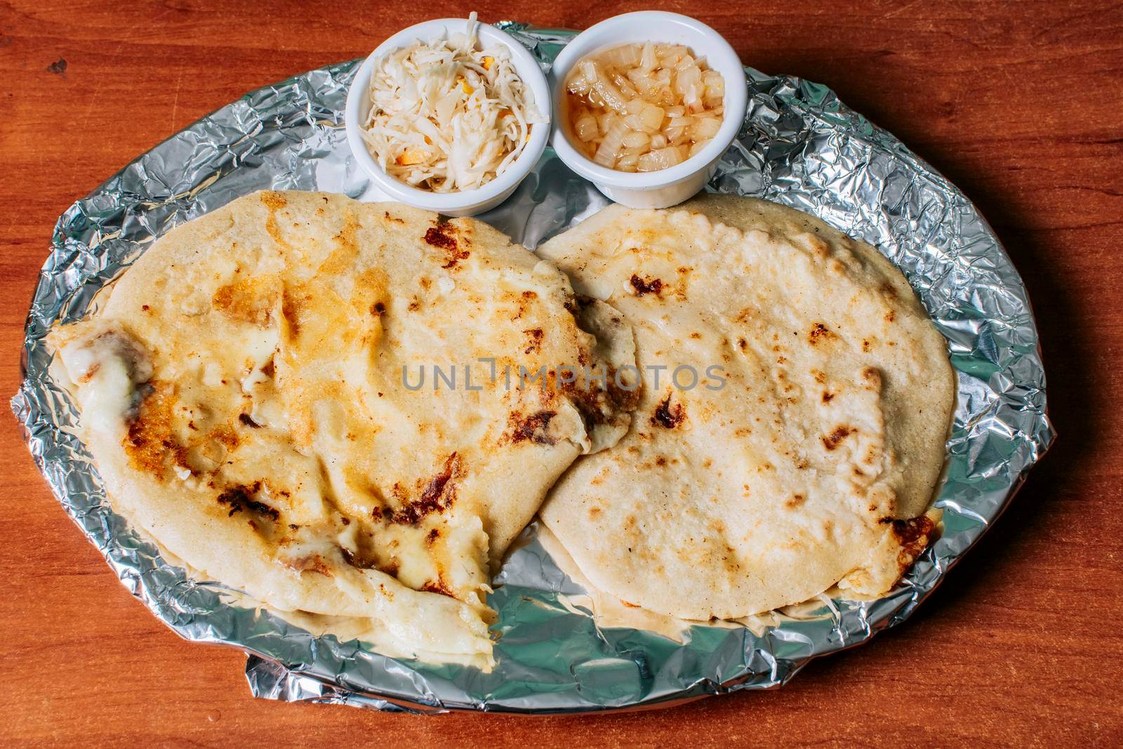 Top view of two Nicaraguan pupusas served with salad on the table. Delicious Salvadoran pupusas with melted cheese served on the table. Traditional pupusas served with salad on the table by isaiphoto