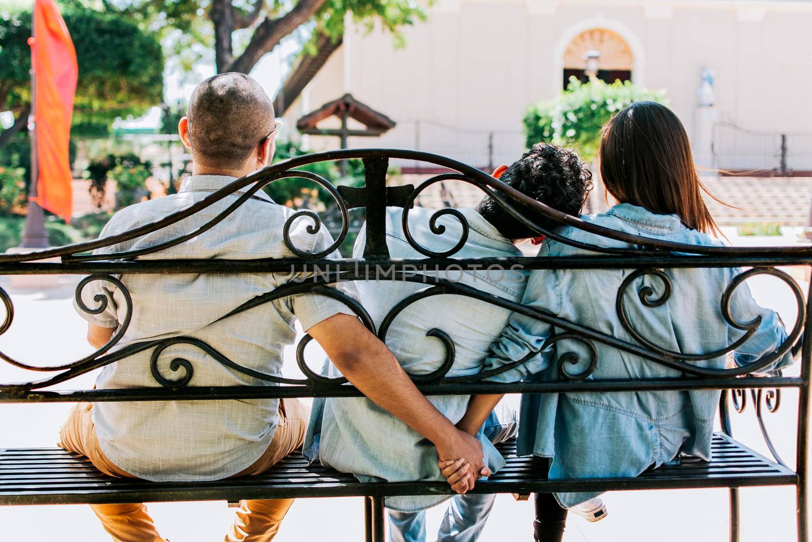 Unfaithful couple holding hands on a park bench, Cheating girlfriend with her boyfriend holding another man's hand in a park. love triangle concept