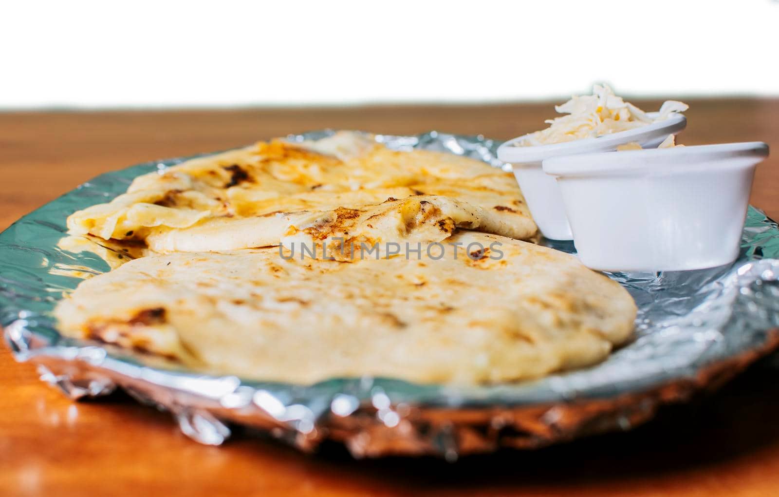 Traditional pupusas served with salad on the table. Two Nicaraguan pupusas with salad on the table, Side view of delicious Salvadoran pupusas with cheese served on the table.