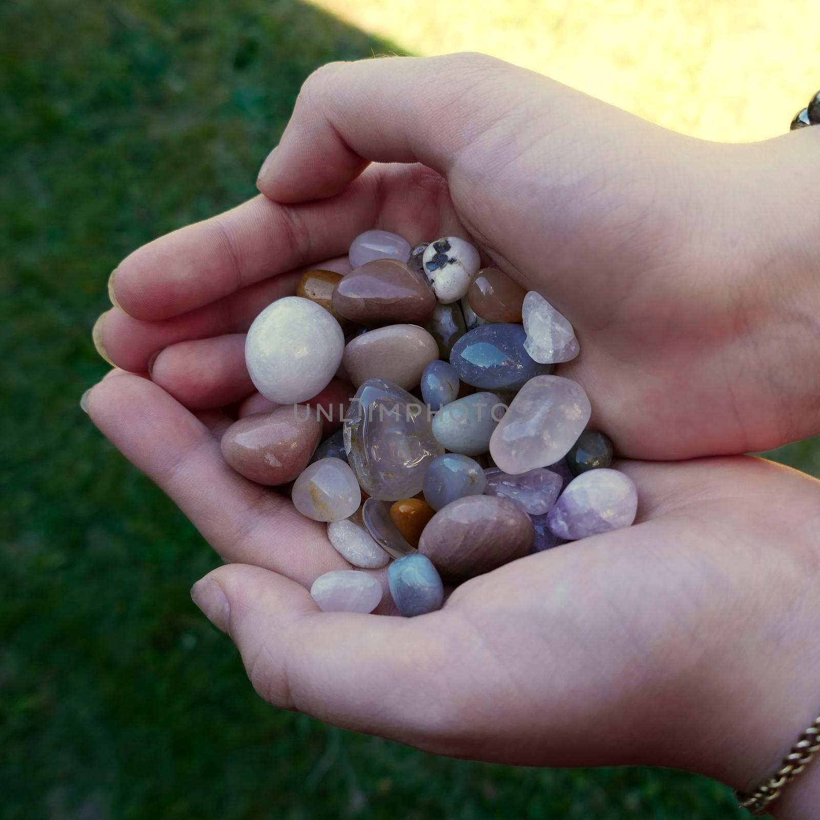 Tumble finished mixture of semi-precious stones in the hands of a girl