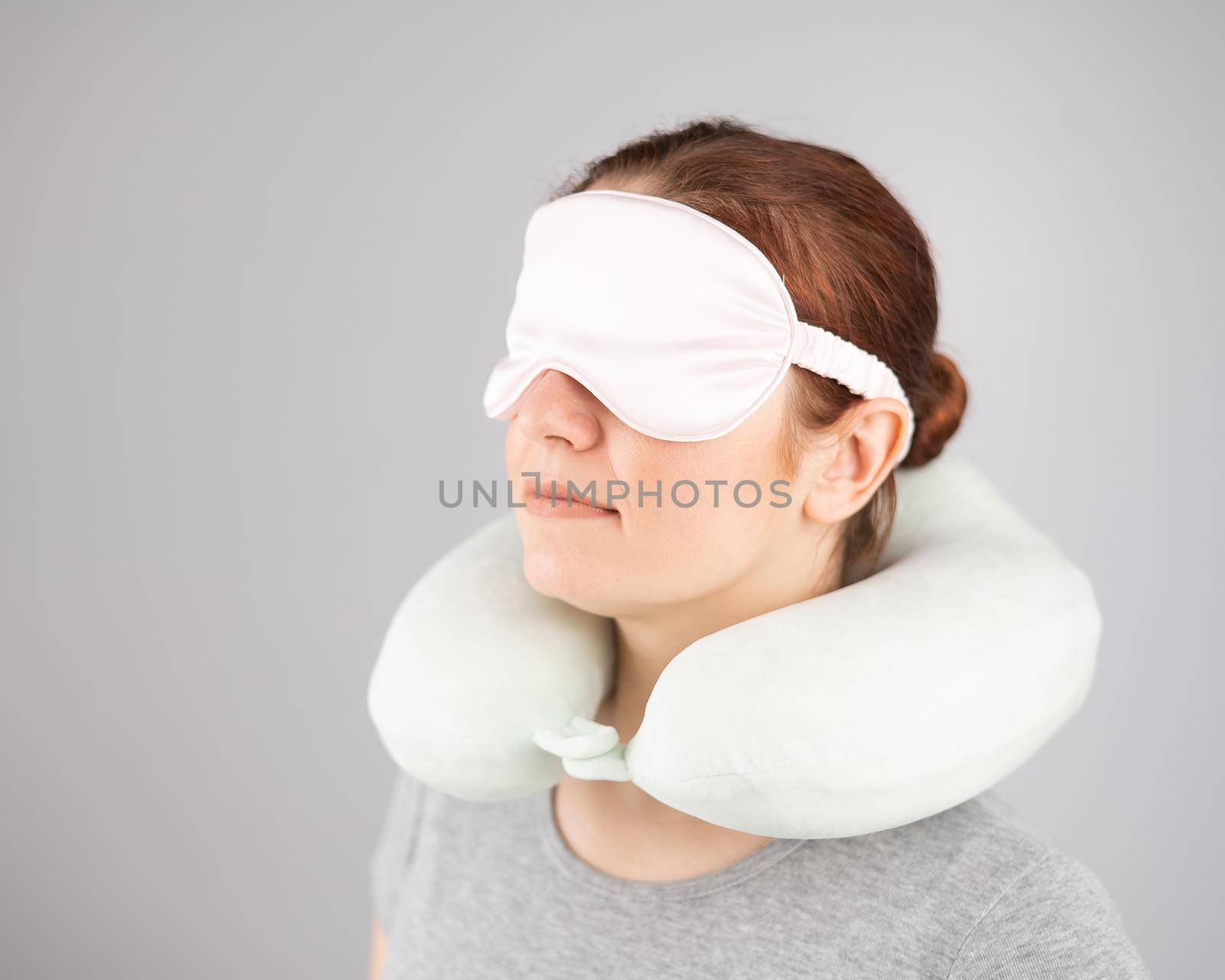 Caucasian woman with travel pillow and sleeping mask isolated on white background