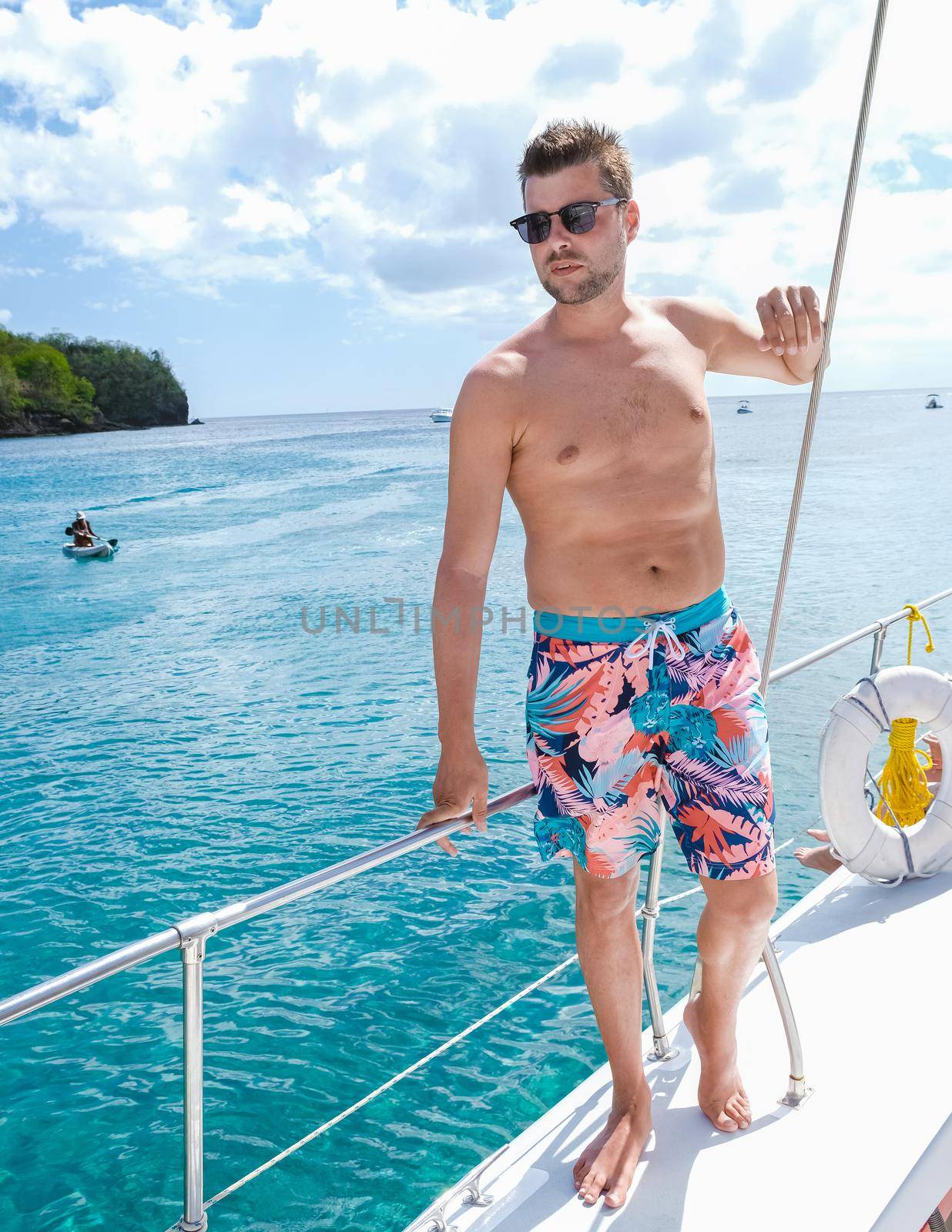 young men in swim short on a boat trip with a catamaran on vacation in Saint Lucia, luxury holiday Saint Lucia Caribbean, men on vacation at the tropical Island of Saint Lucia Caribbean.