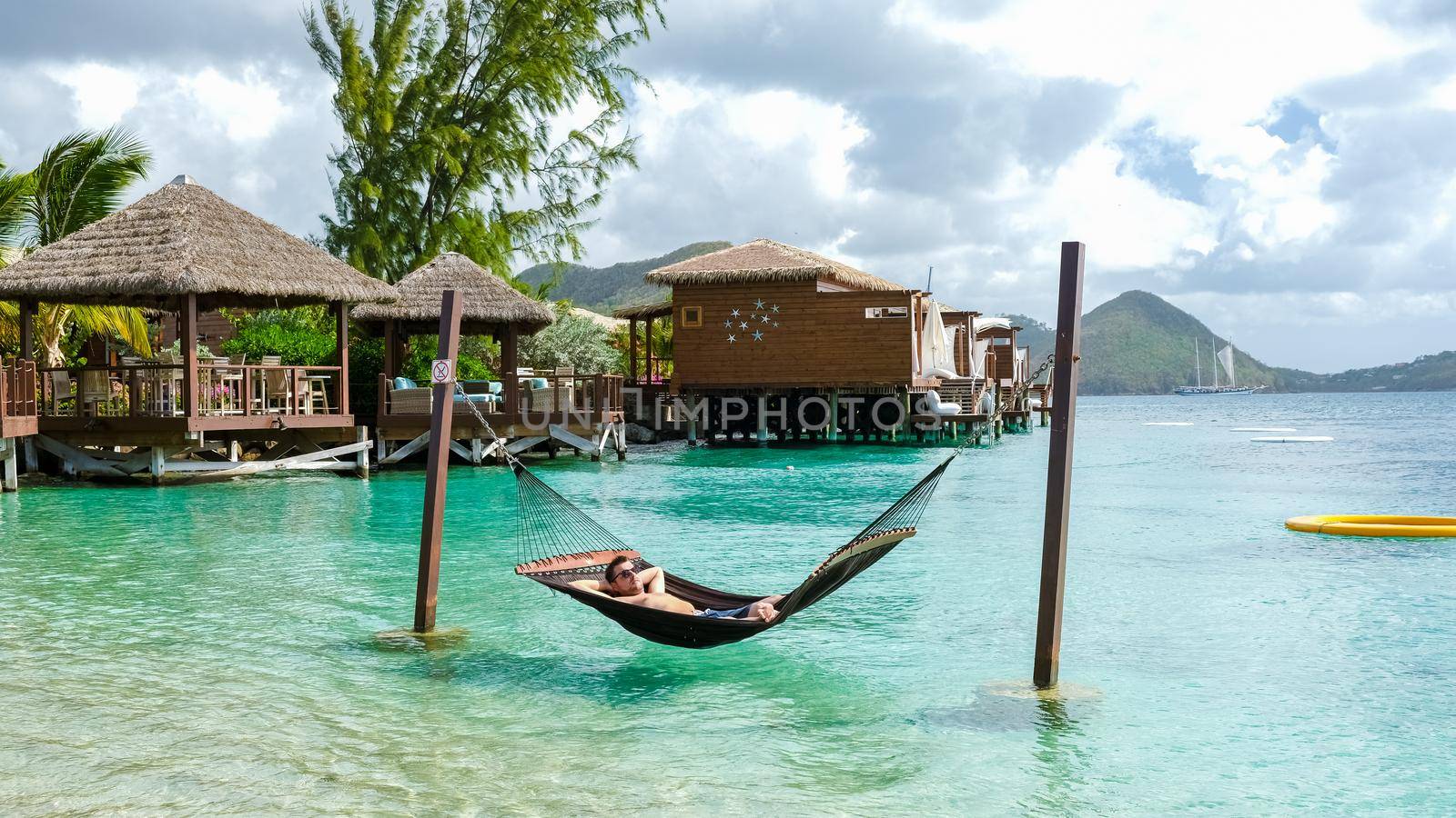 young men in hammocks in the ocean at the beach of the tropical Island in the Caribbean. luxury holiday vacation on a tropical island