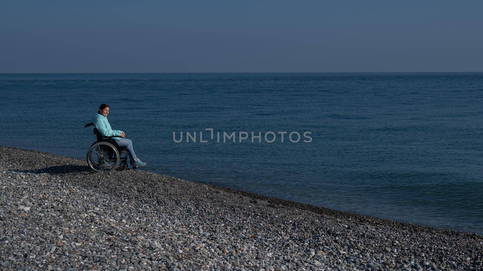 Pacified caucasian woman in a wheelchair on the seashore