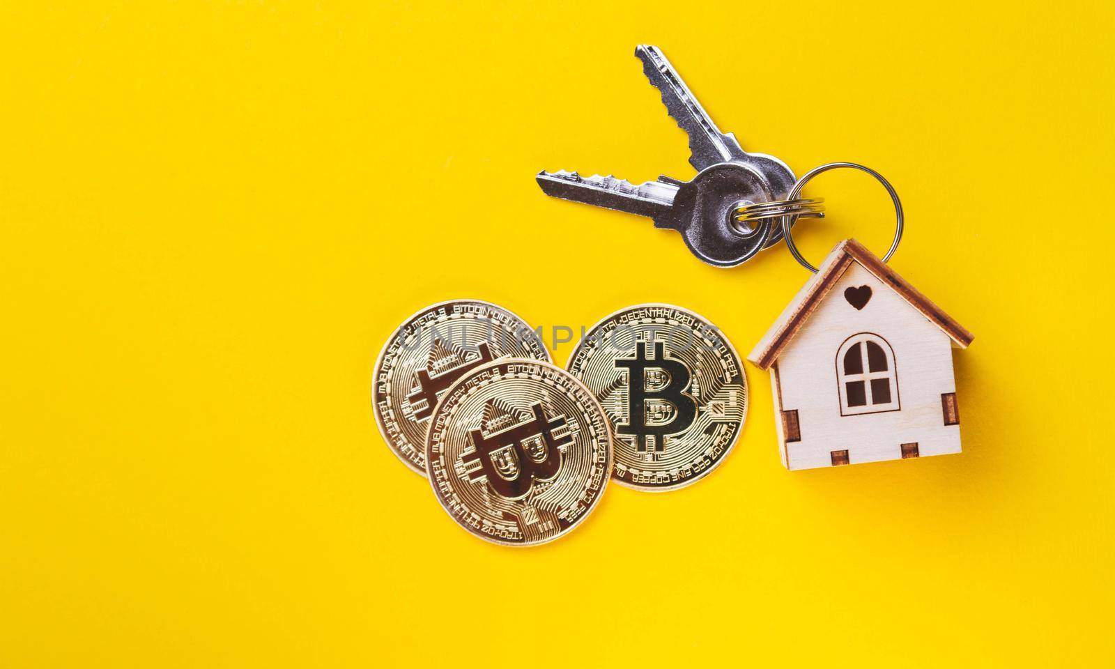 Buying real estate for cryptocurrency. Housing and bitcoins. Coins and house keys. Small wooden house and bitcoin coin.