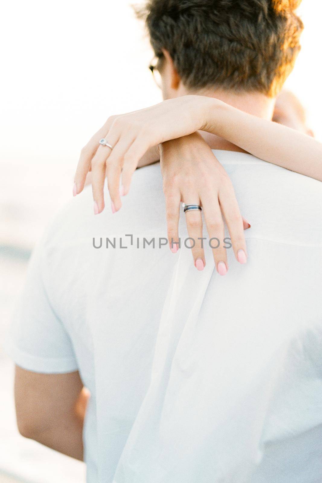 Women hands hug a man by the neck. Close-up. Back view. High quality photo