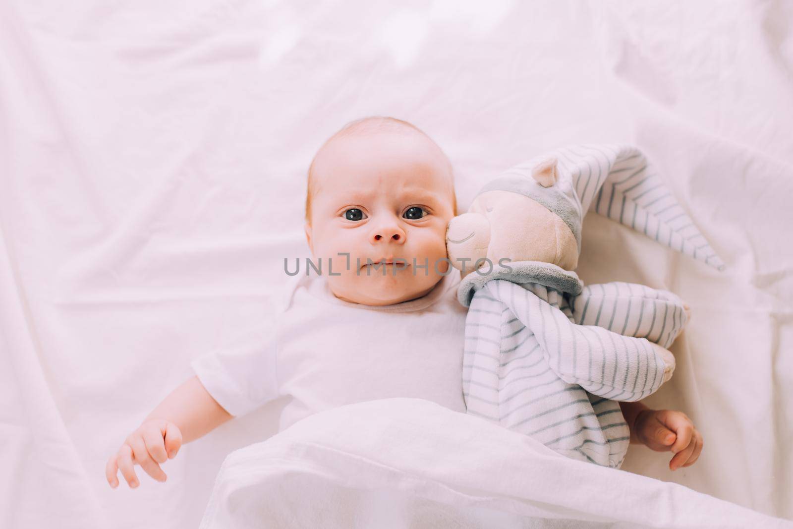 The baby is lying in his crib and looking at the camera . A happy child. Children's article. Copy Space