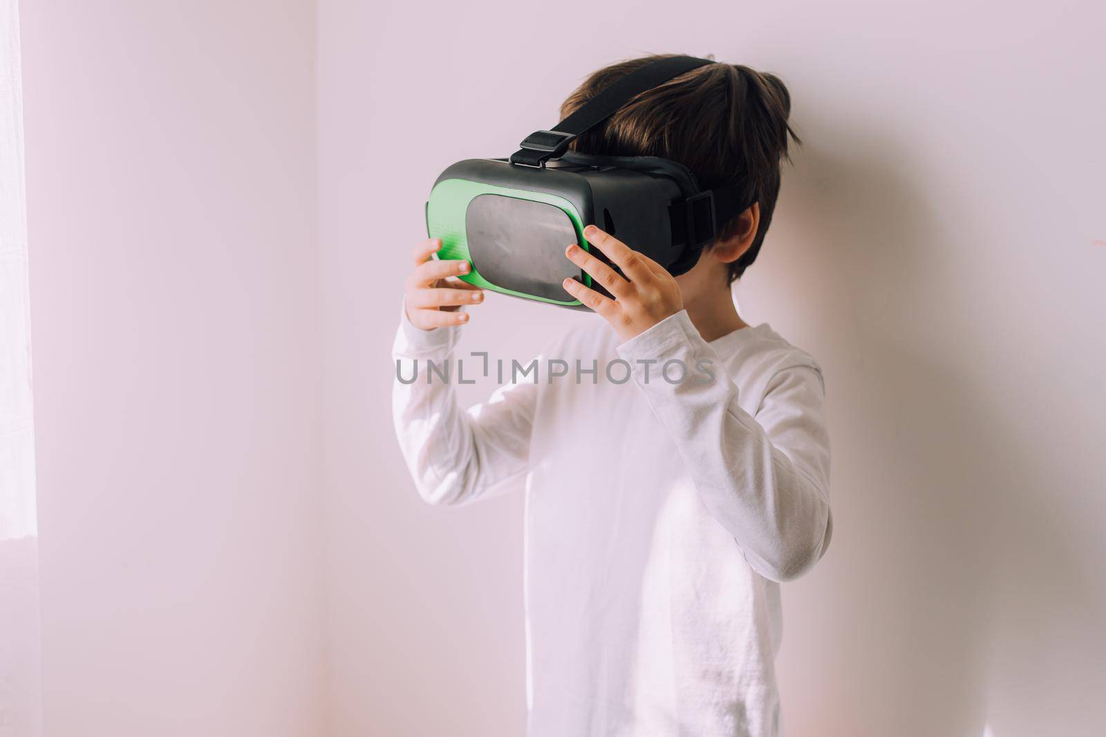 A boy is playing vr glasses on a white copyspace wall . An article about modern gadgets. An article about modern technologies. Place under the text