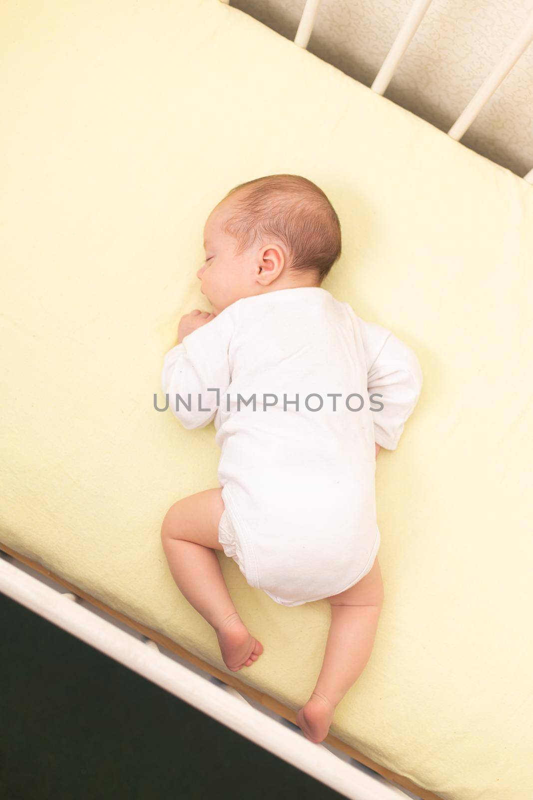 The baby sleeps in the copy space crib . Advertising of children's goods. Illustrating children's articles. A small child. A newborn. A child's dream.