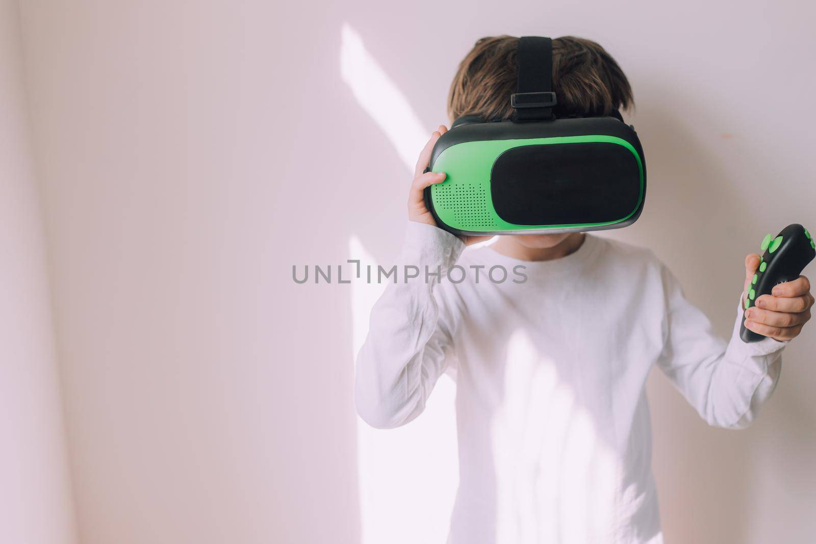 A boy is playing vr glasses on a white copyspace wall . An article about modern gadgets. An article about modern technologies. Place under the text