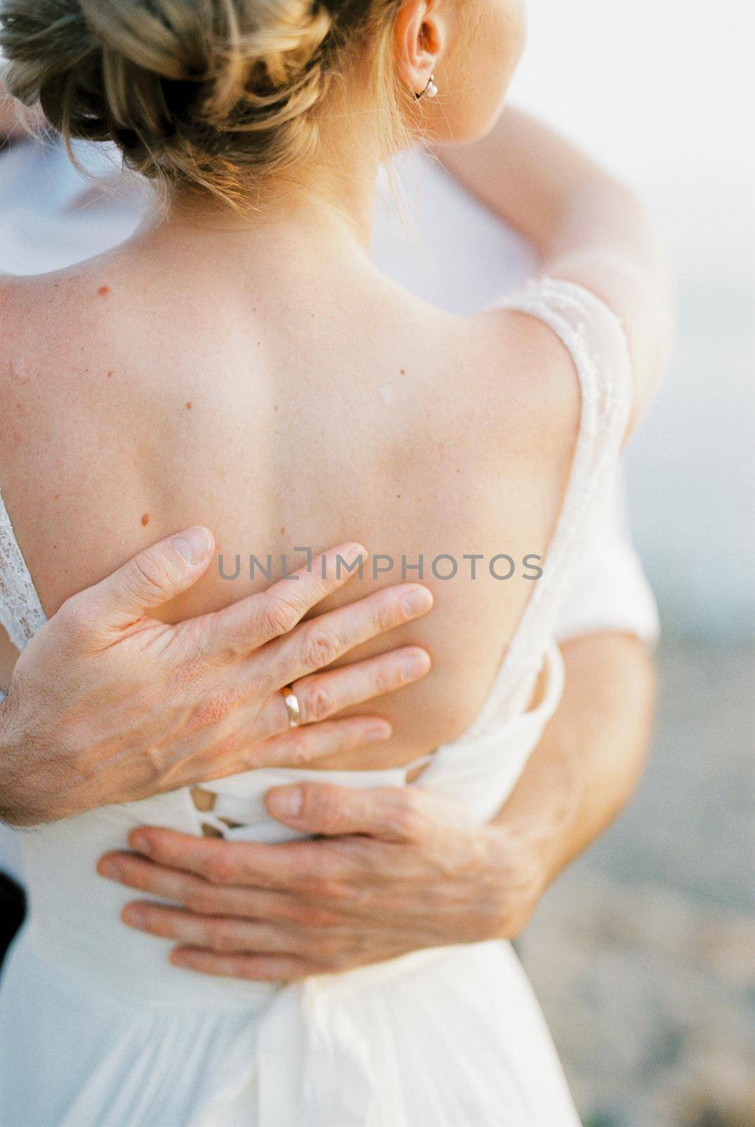 Groom arms hug bride back. Close-up. High quality photo