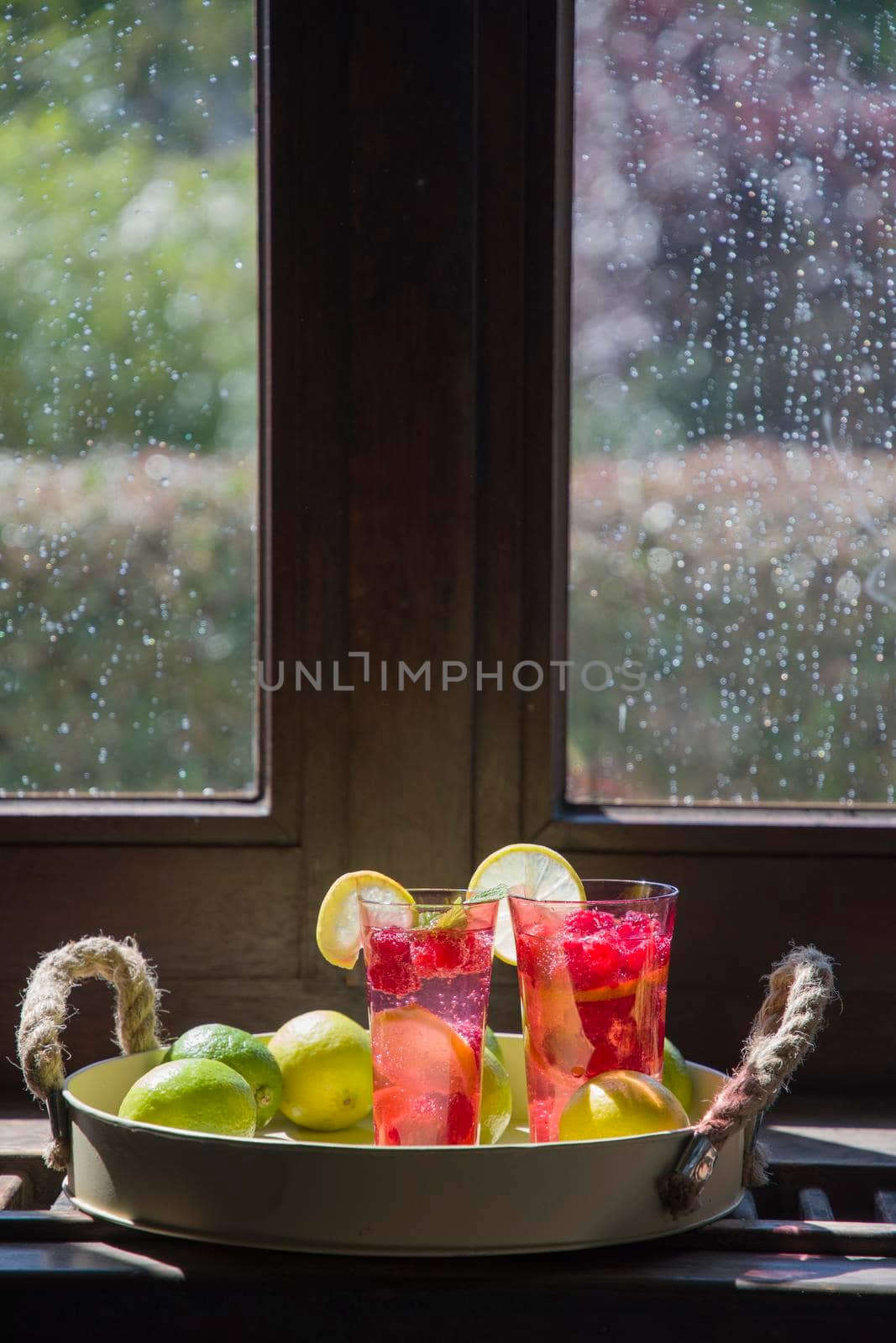 Refreshing raspberry and lime lemonade in pink glasses on the windowsill by KaterinaDalemans