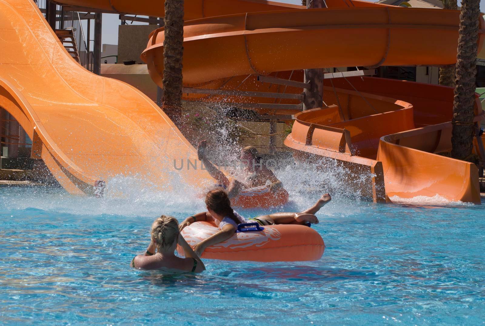 Children and women swim in the pool and slide down the water slides into the water at the water park in the hotel, refreshing fun on a summer day, High quality photo