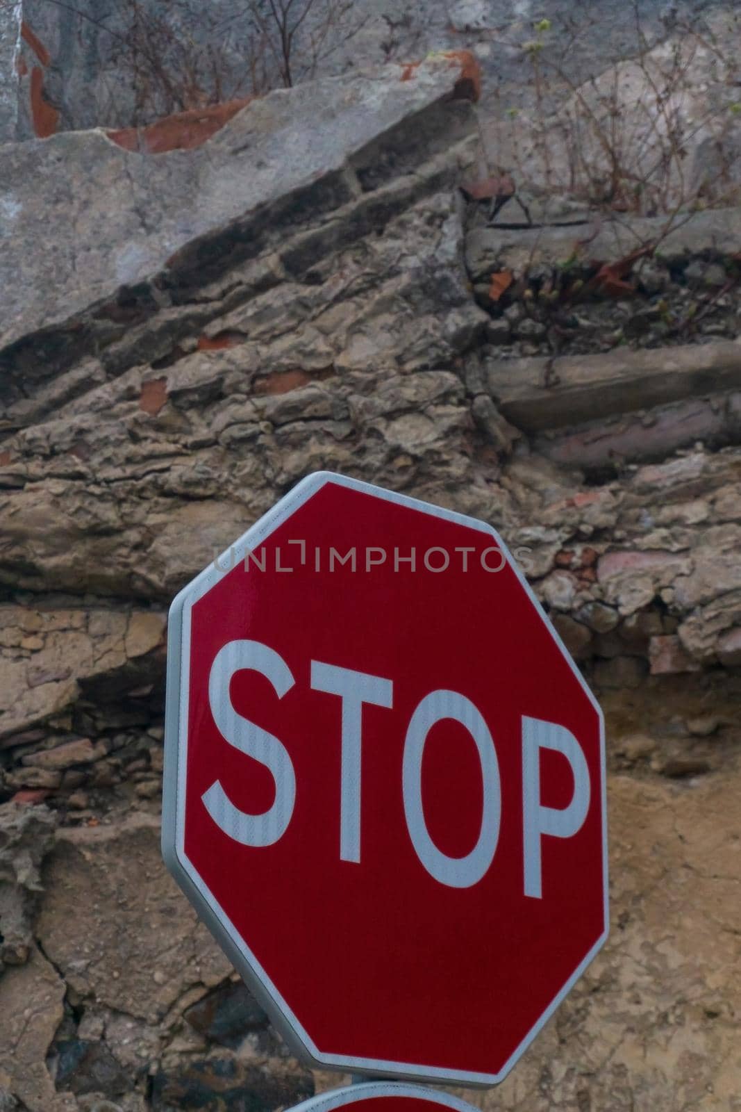 Red stop sign on the background of a destroyed brick wall close up