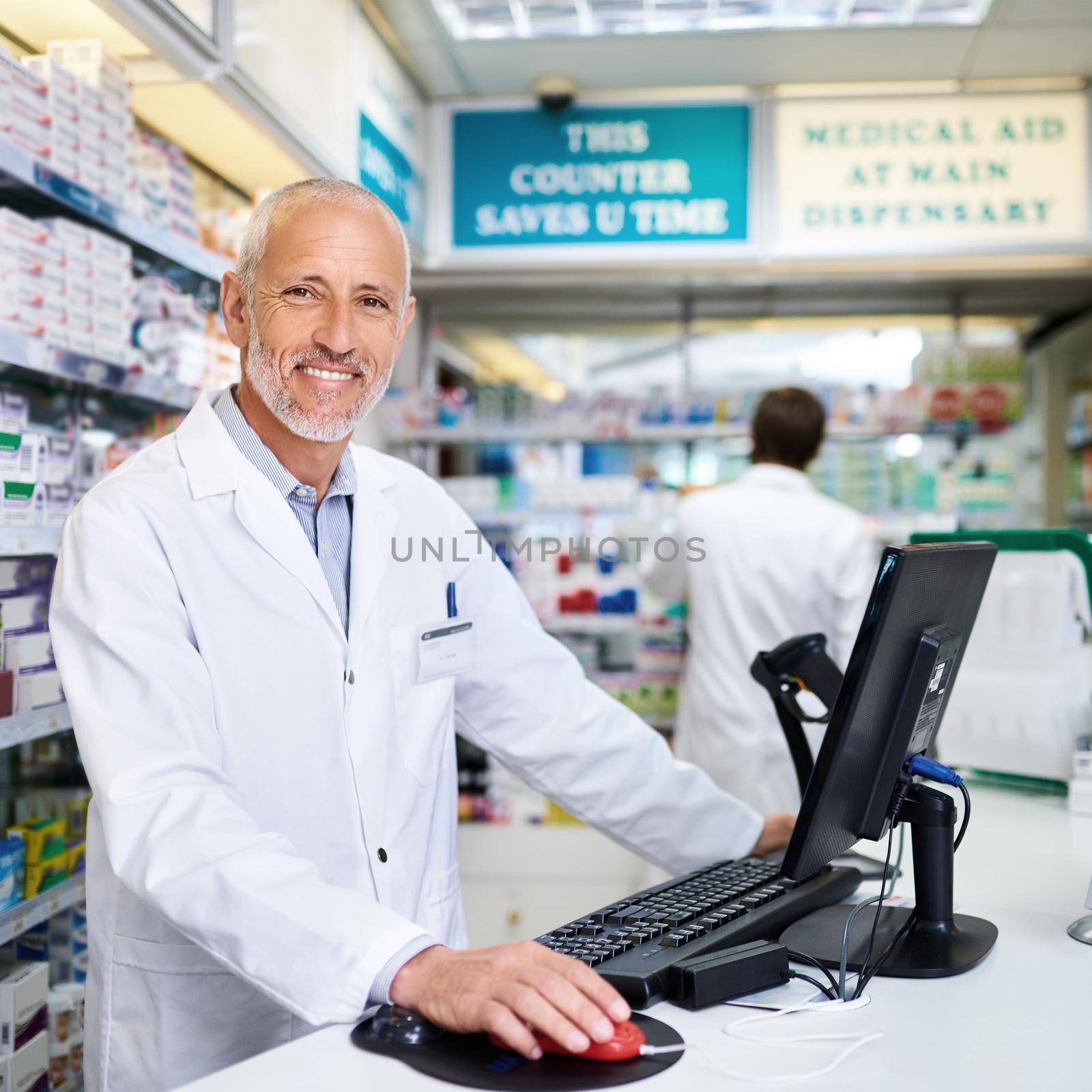 Here to help you get better. Portrait of a mature pharmacist working on a computer in a chemist. by YuriArcurs