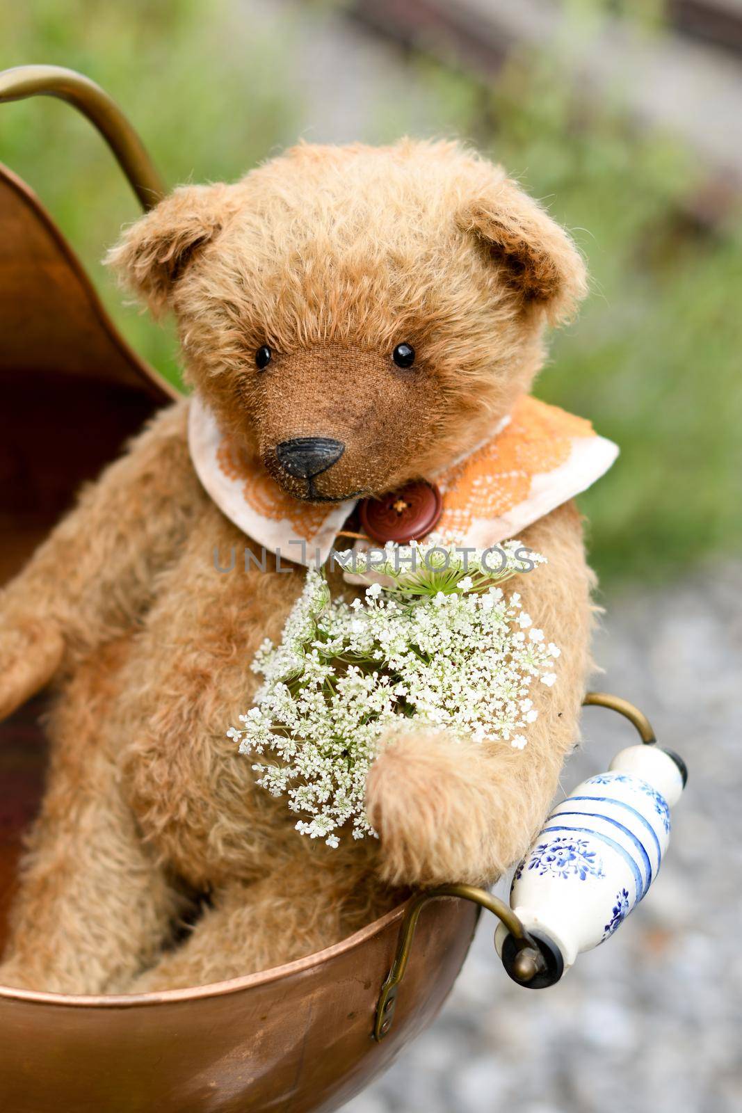 small adorable brown teddy bear sits in a copper pot on an abandoned railroad d alone, plush friend handmade, vintage and retro. High quality photo