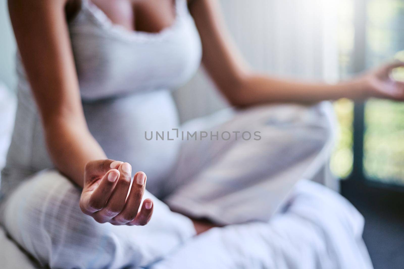 Prenatal yoga may be the cure for what ails you. a pregnant woman doing yoga in her bedroom. by YuriArcurs