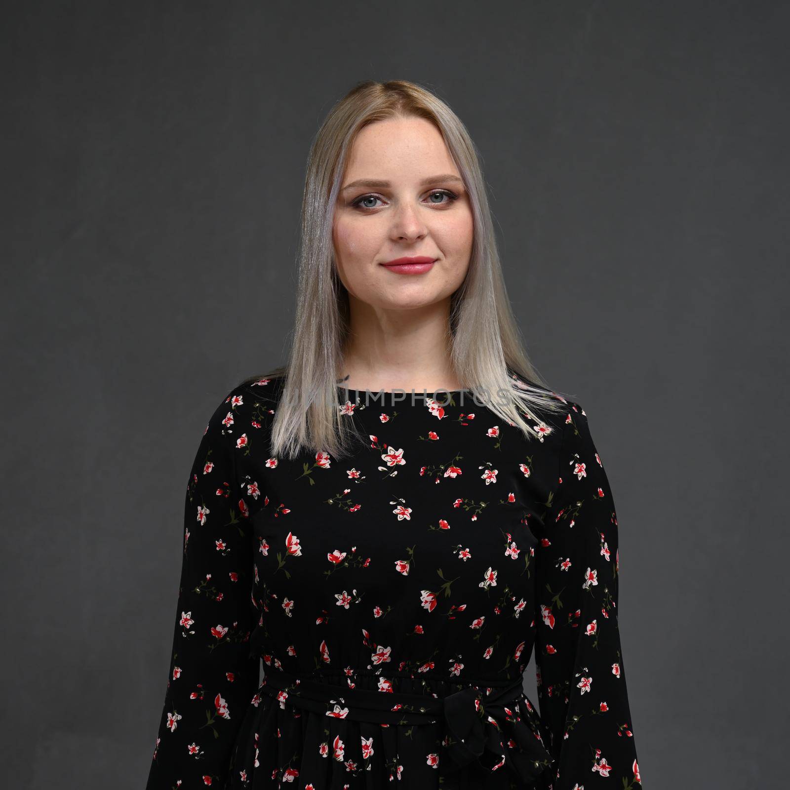 Portrait of a beautiful young blonde woman with long straight hair on a gray background