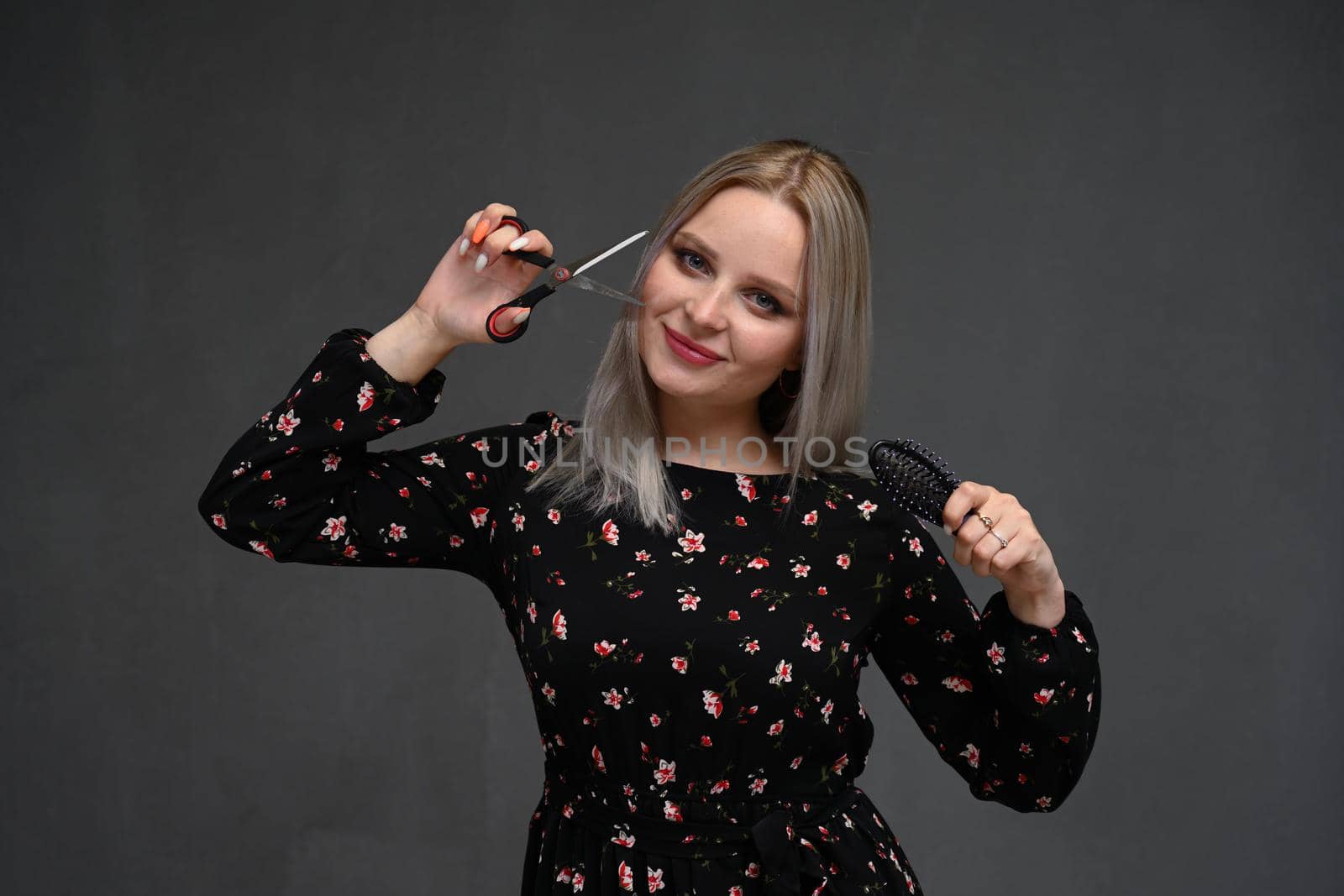 attractive smiling woman portrait on gray background with scissors