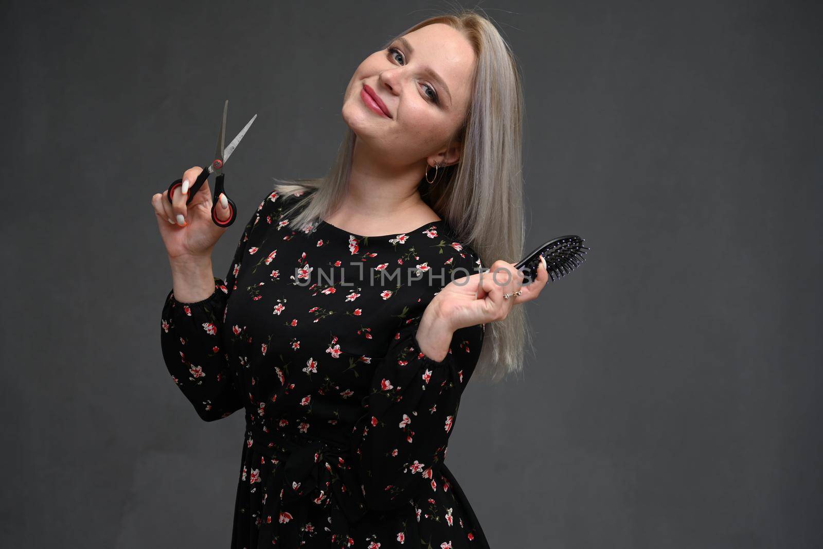 Beautiful girl with blond hair with scissors and a comb in her hands