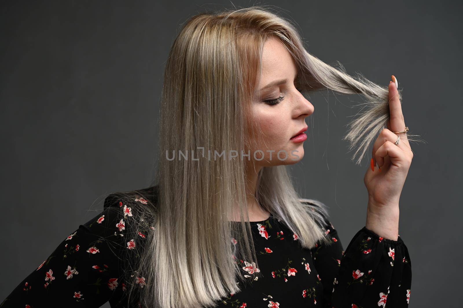 Beautiful girl with curly hair blonde looking at her hair to the side .