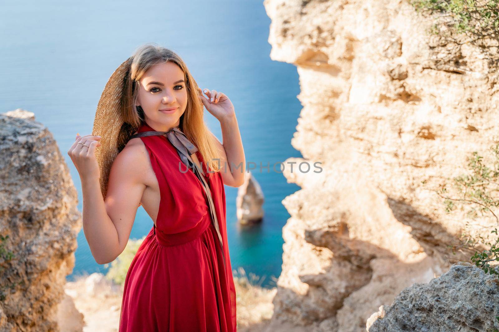 A woman in a red flying dress fluttering in the wind, against the backdrop of the sea