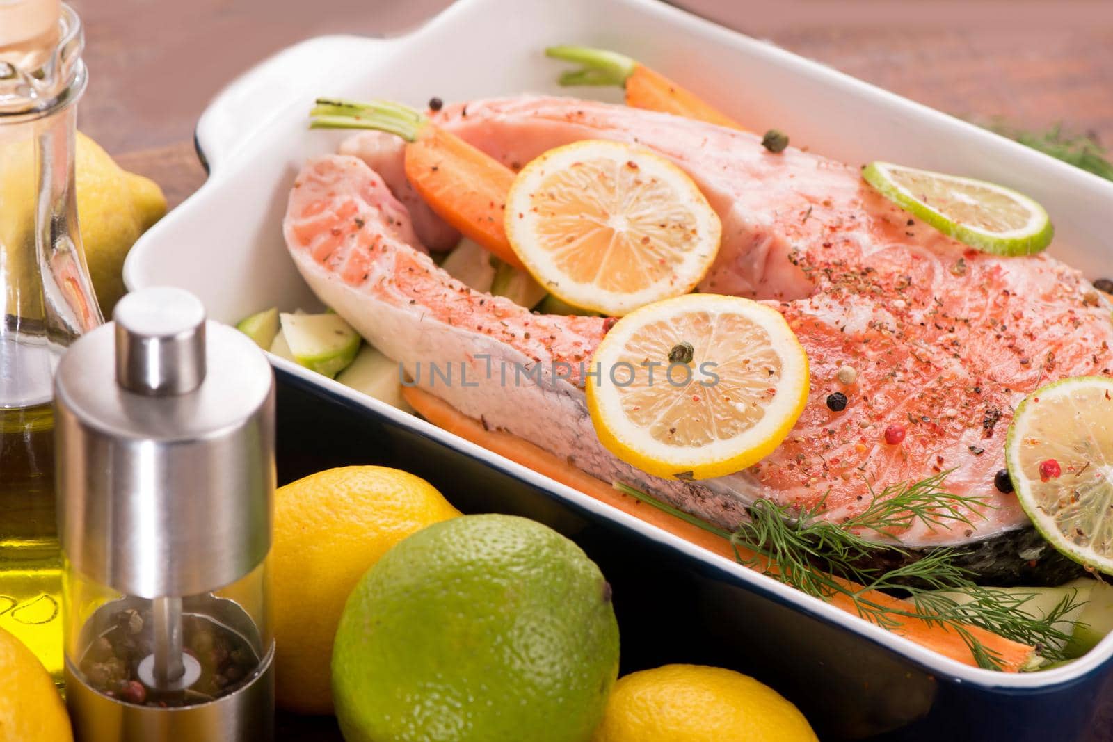 Raw fish is ready for baking. Salmon steak. Red fish and sliced lemons on white by aprilphoto