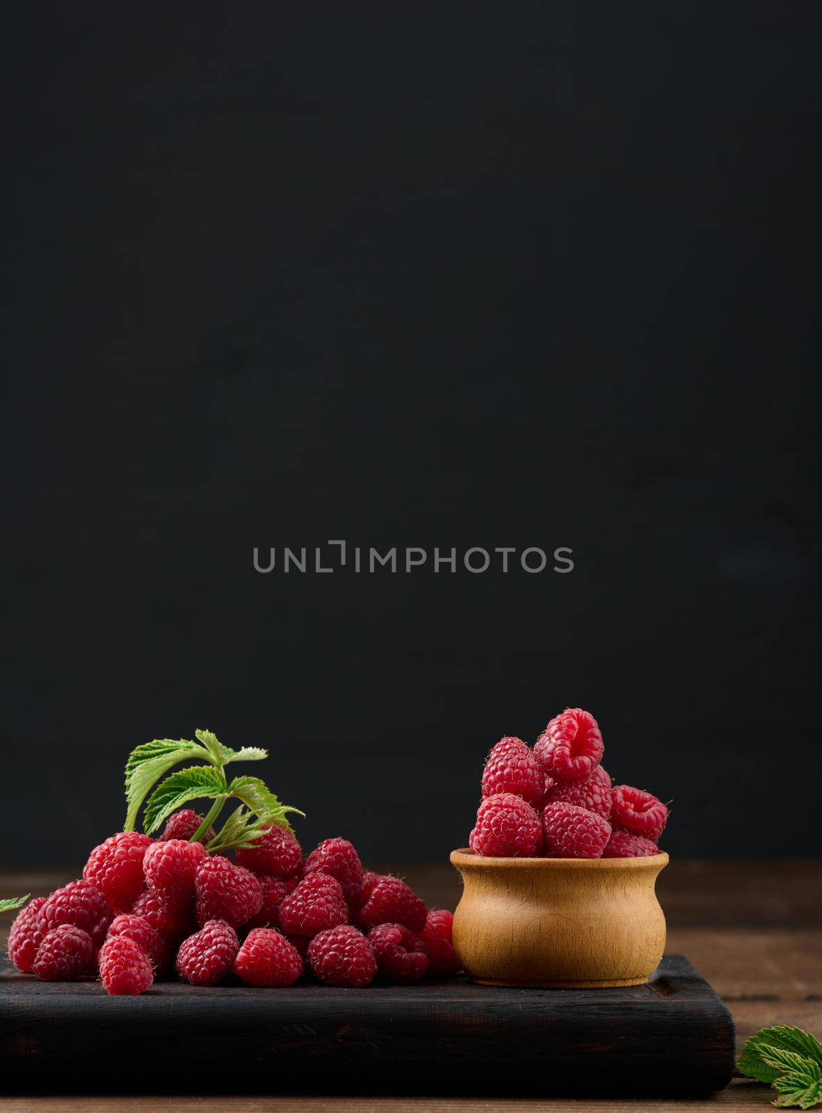 Ripe red raspberries on a brown wooden board