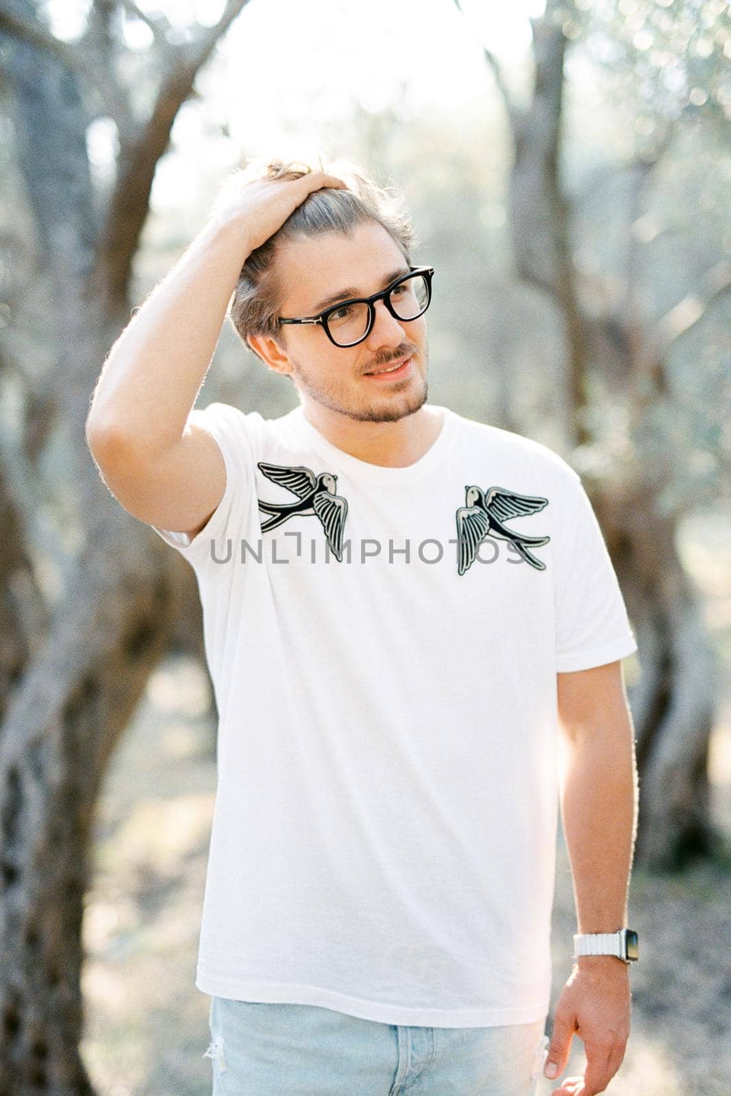 Young man with glasses straightens his hair with his hand. High quality photo