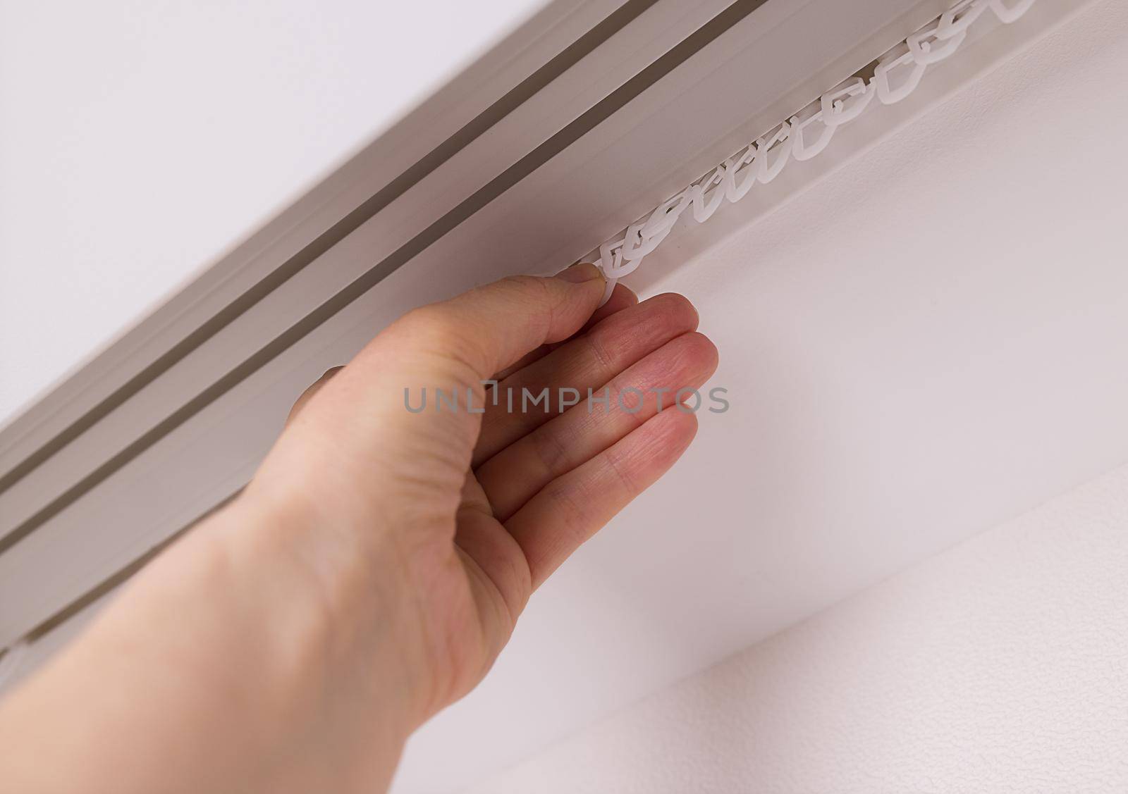 close-up, the hand of a white woman prepares hooks on the window to hang the curtains. Copy space for design Decoration concept, home decor, interior designer. New apartments. Home improvement service
