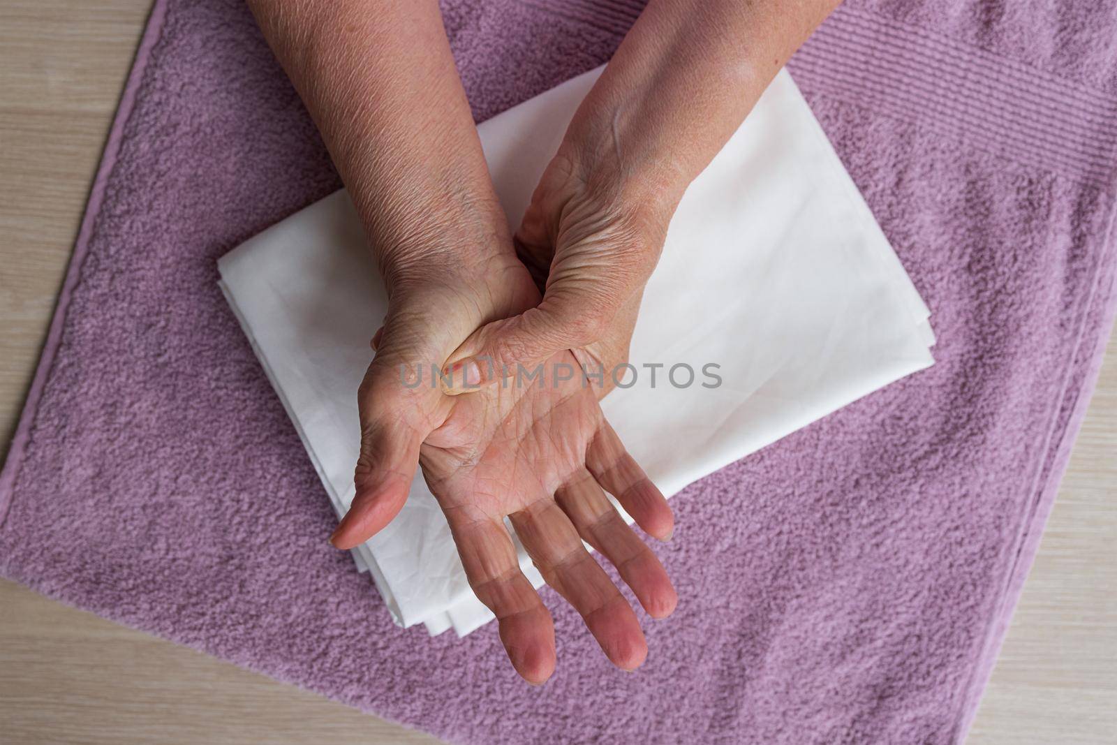 step by step instructions step 2. Close-up, the hands of elderly white woman with arthritis. Background white towel, top view, makes himself massage. The concept of prevention of neurological diseases