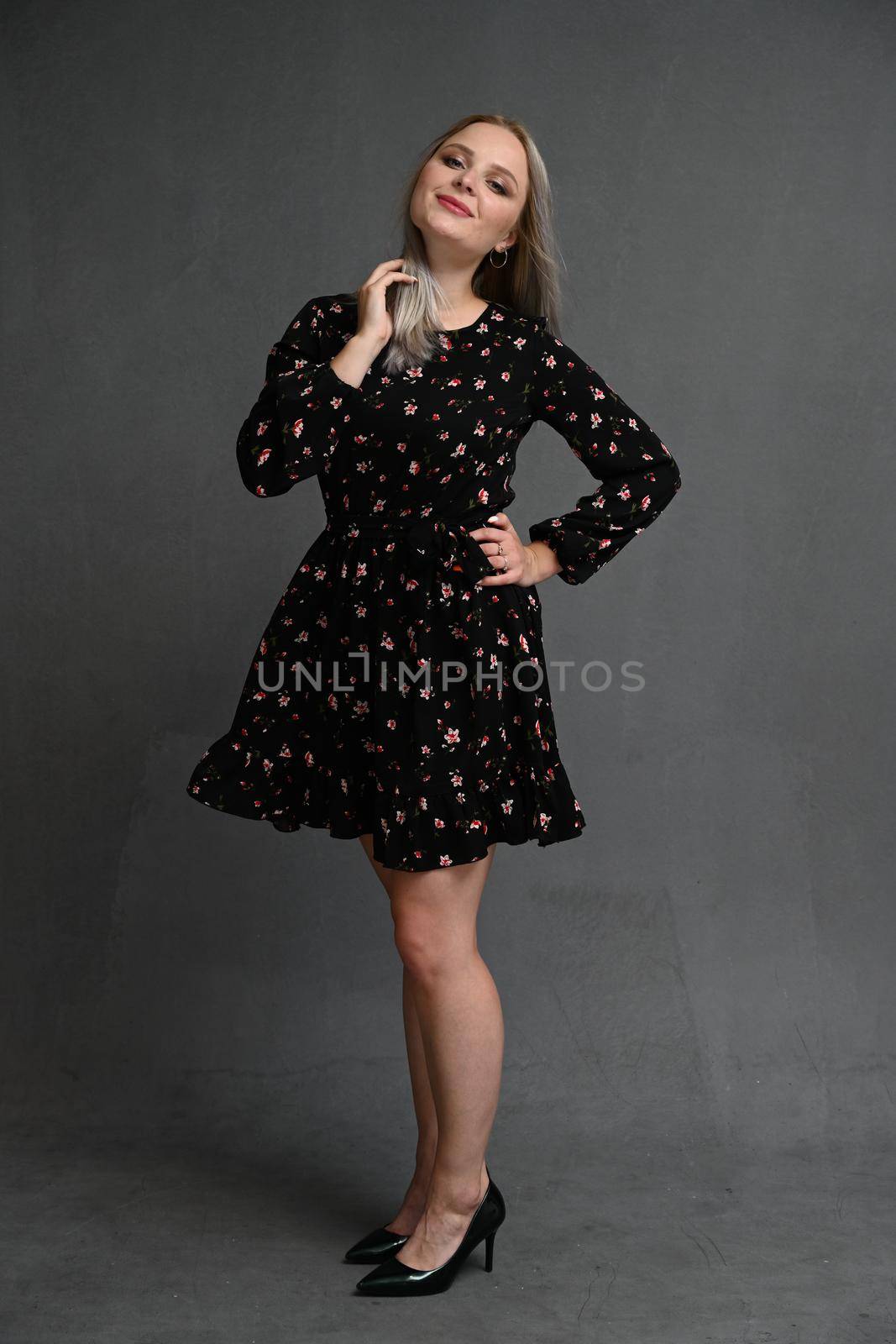 Full length portrait of a happy beautiful girl wearing dress posing while standing isolated over gray background by chichaevstudio