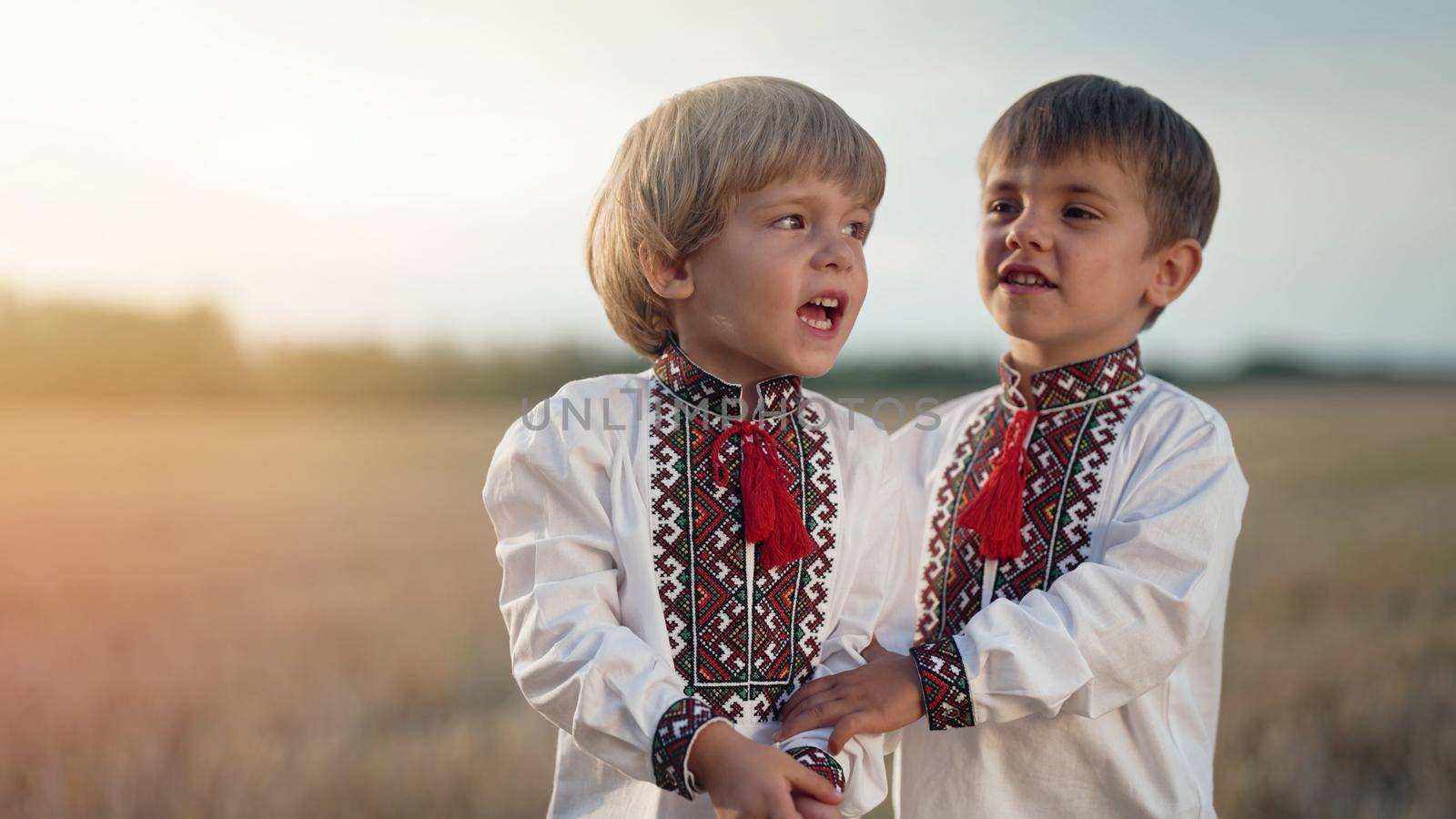 Beautiful portrait of little ukrainian boys singing song in wheat field after harvesting. Children in traditional embroidery vyshyvanka shirt. Ukraine, national costume, happy childhood future. photo