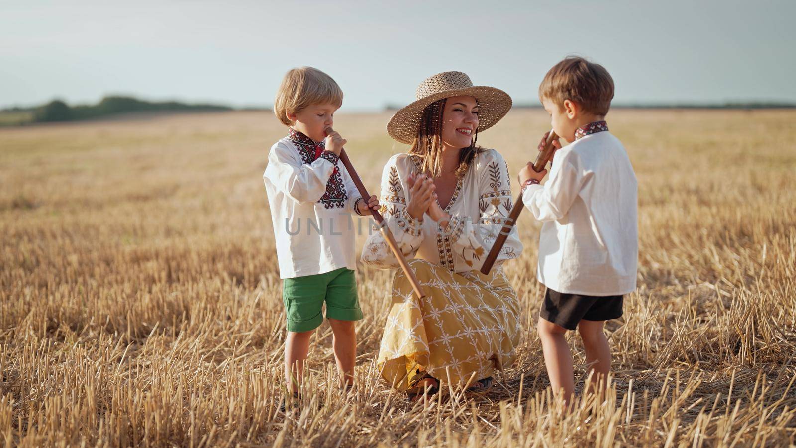 Boys playing on wooden flutes - sopilka. Ukrainian mother with children sons in wheat field. Woman in embroidery vyshyvanka. Ukraine, traditional music instrument, melody, song by kristina_kokhanova