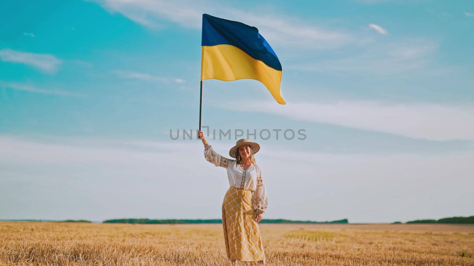 Ukrainian woman waving national flag in wheat field after harvesting. Charming rural lady in embroidery vyshyvanka. Ukraine, independence, freedom, patriot symbol, VICTORY, win in war. by kristina_kokhanova