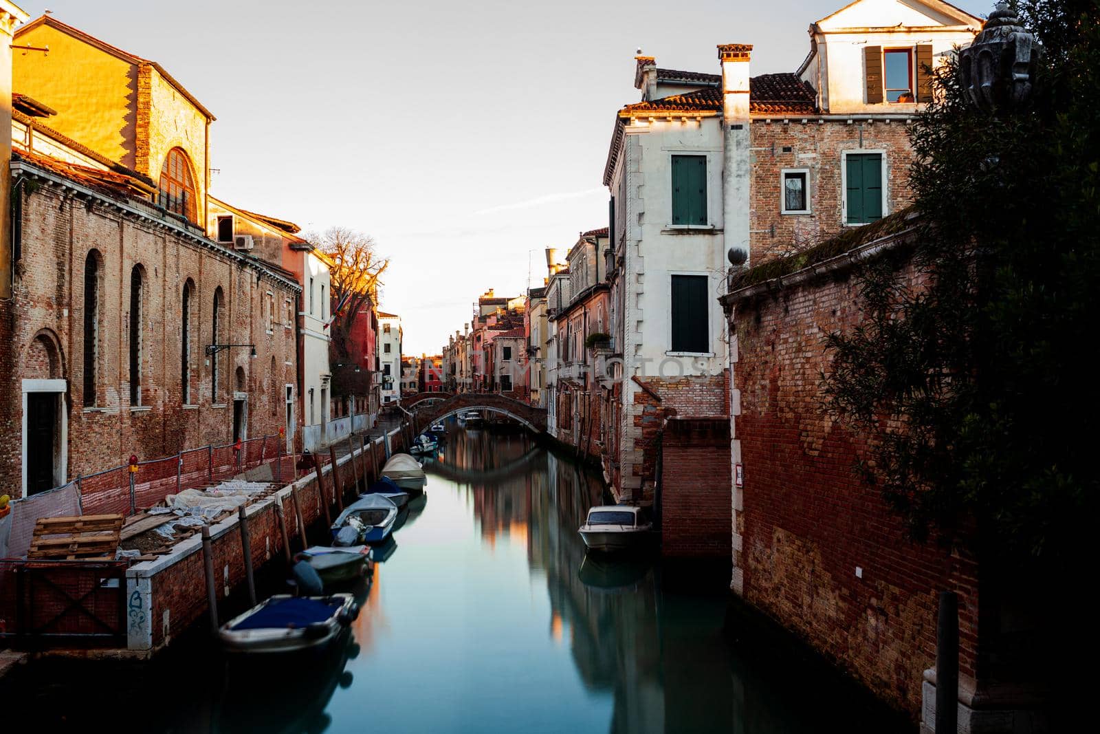 The architectural detail of an old bridge made with red bricks on the typical canal in Venice