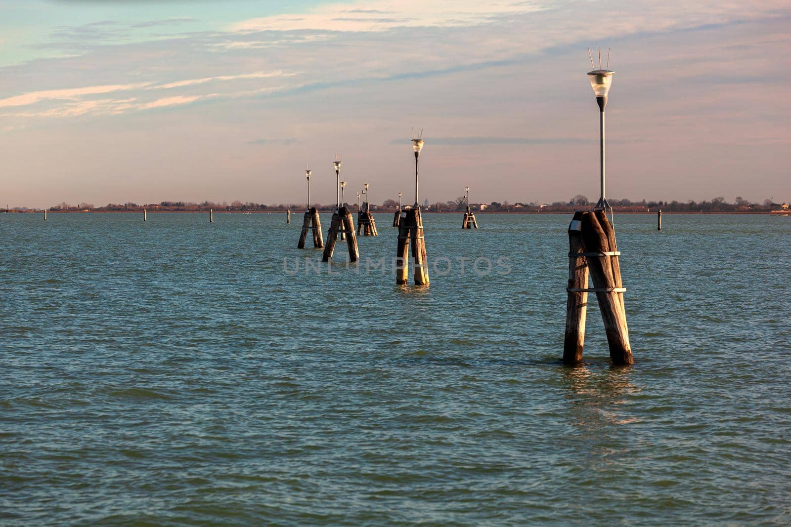 Typical wooden poles in a Venetian lagoon by bepsimage