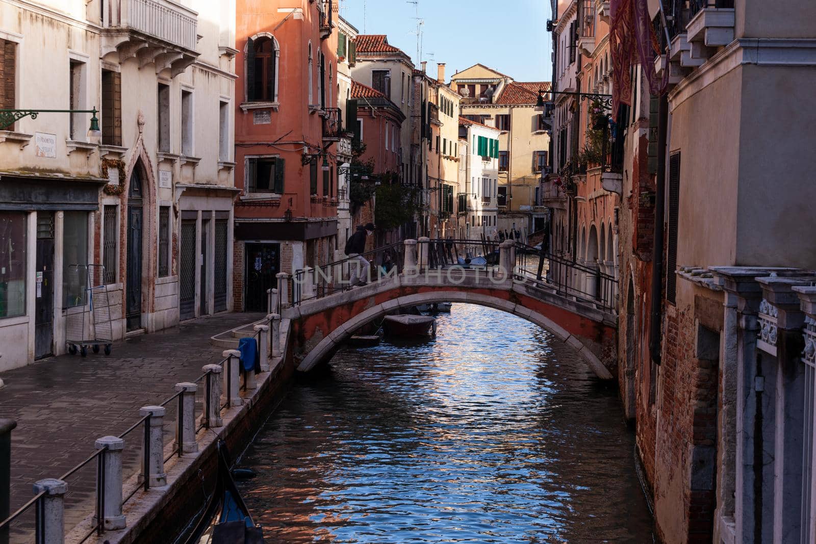 The architectural detail of an old bridge made with red bricks on the typical canal in Venice