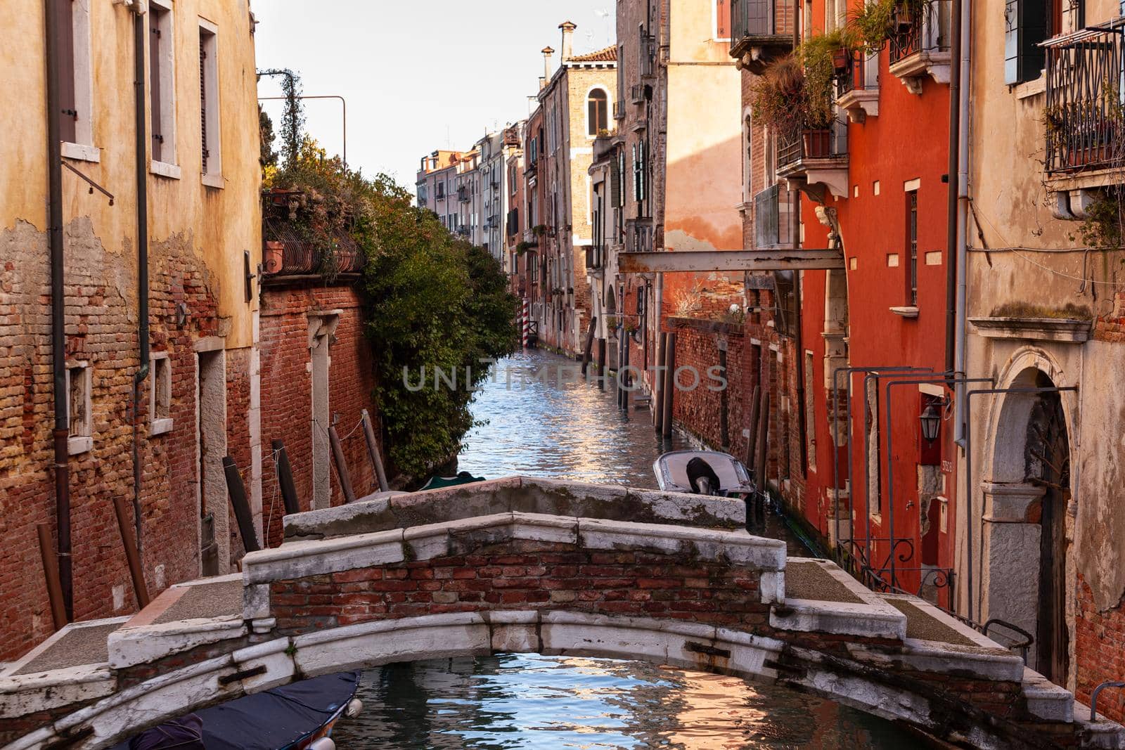 The architectural detail of an old bridge made with red bricks on the typical canal in Venice
