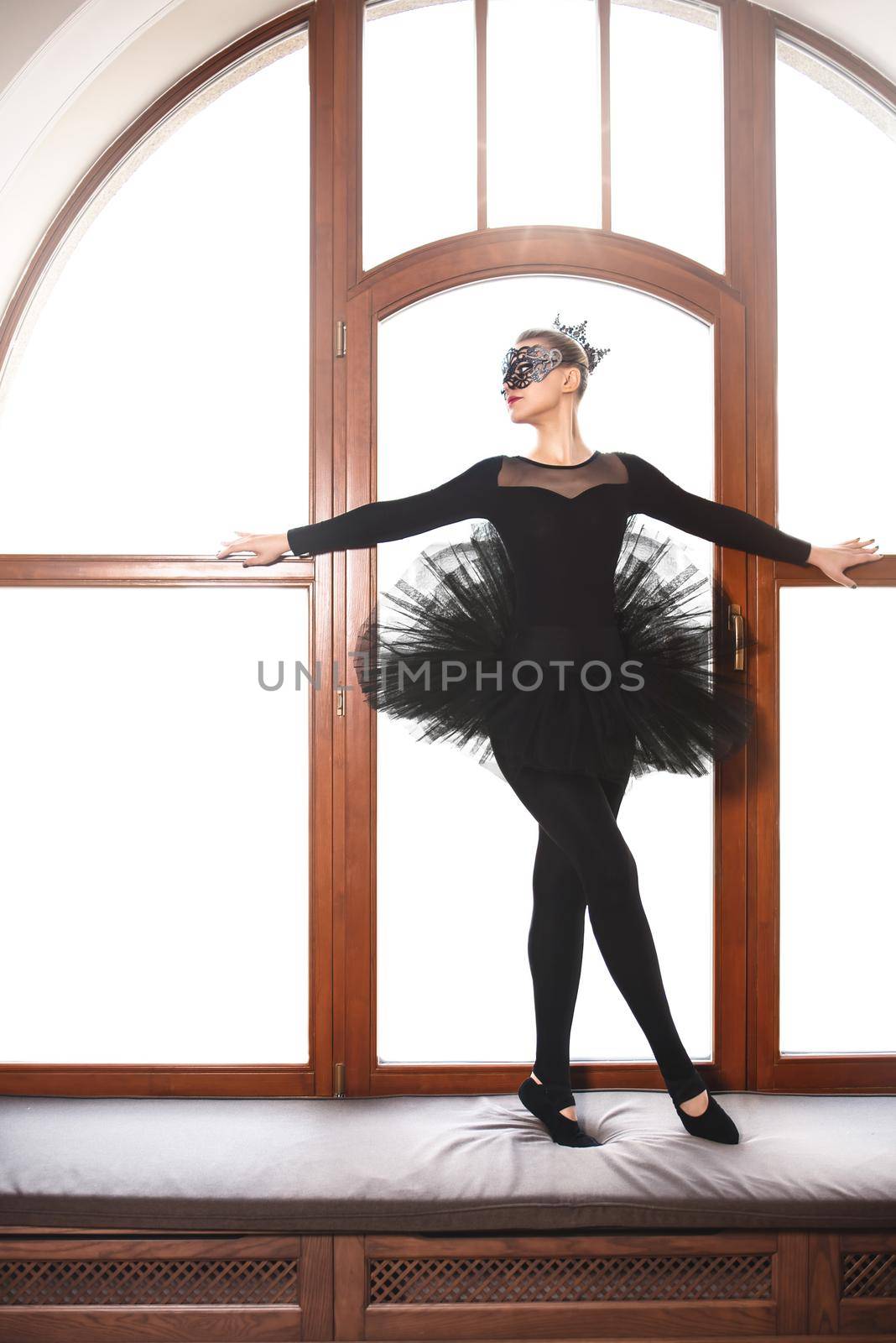 graceful ballerina in black swan dress against wgite background. Young ballet dancer practicing before performance in black tutu, classical dance studio, copy space by Nickstock