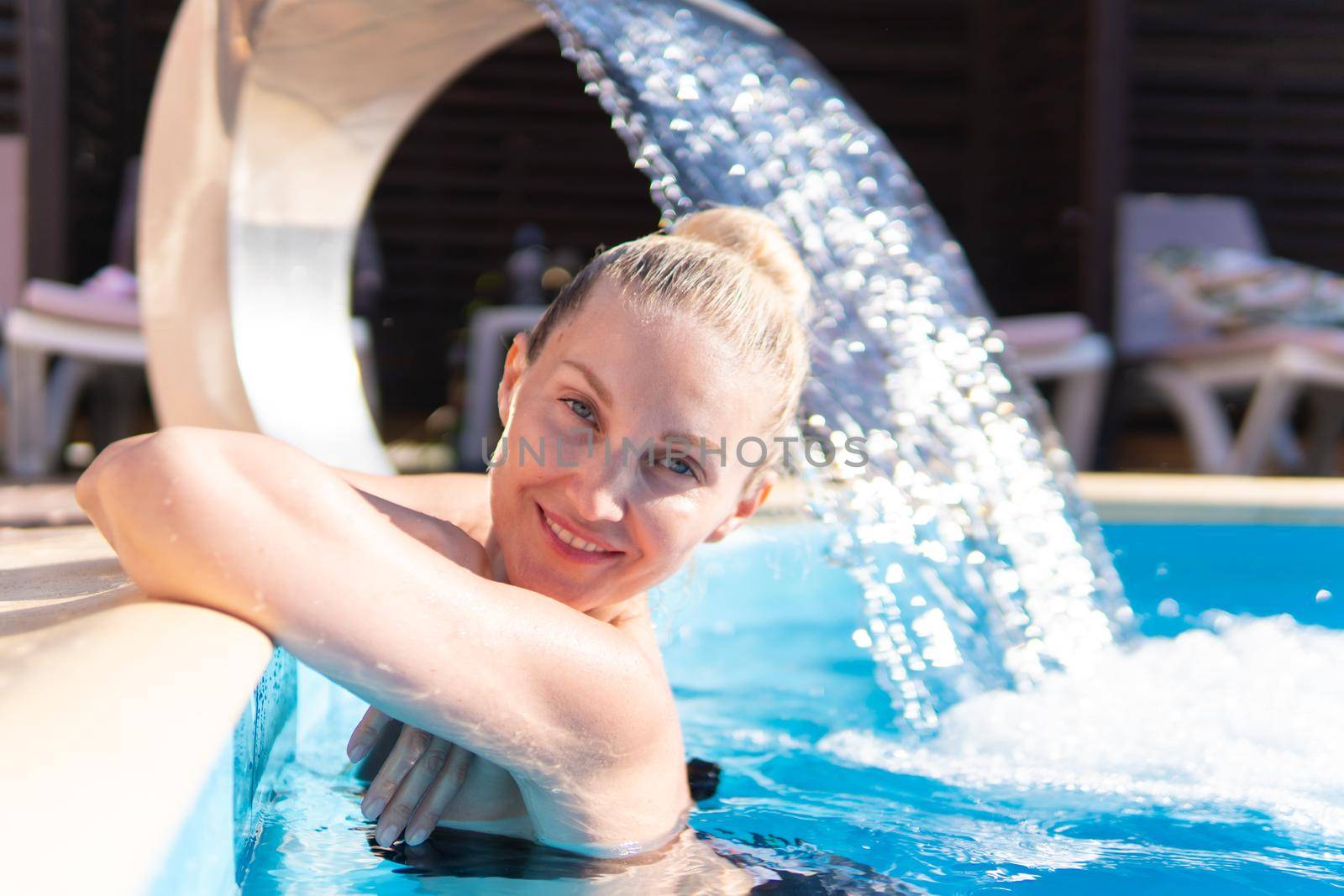 Smiling swimming pool young waterfall woman beautiful luxury outdoor girl, concept vacation enjoying in wash from resort treatment, brunette drop. Holiday gorgeous lady,