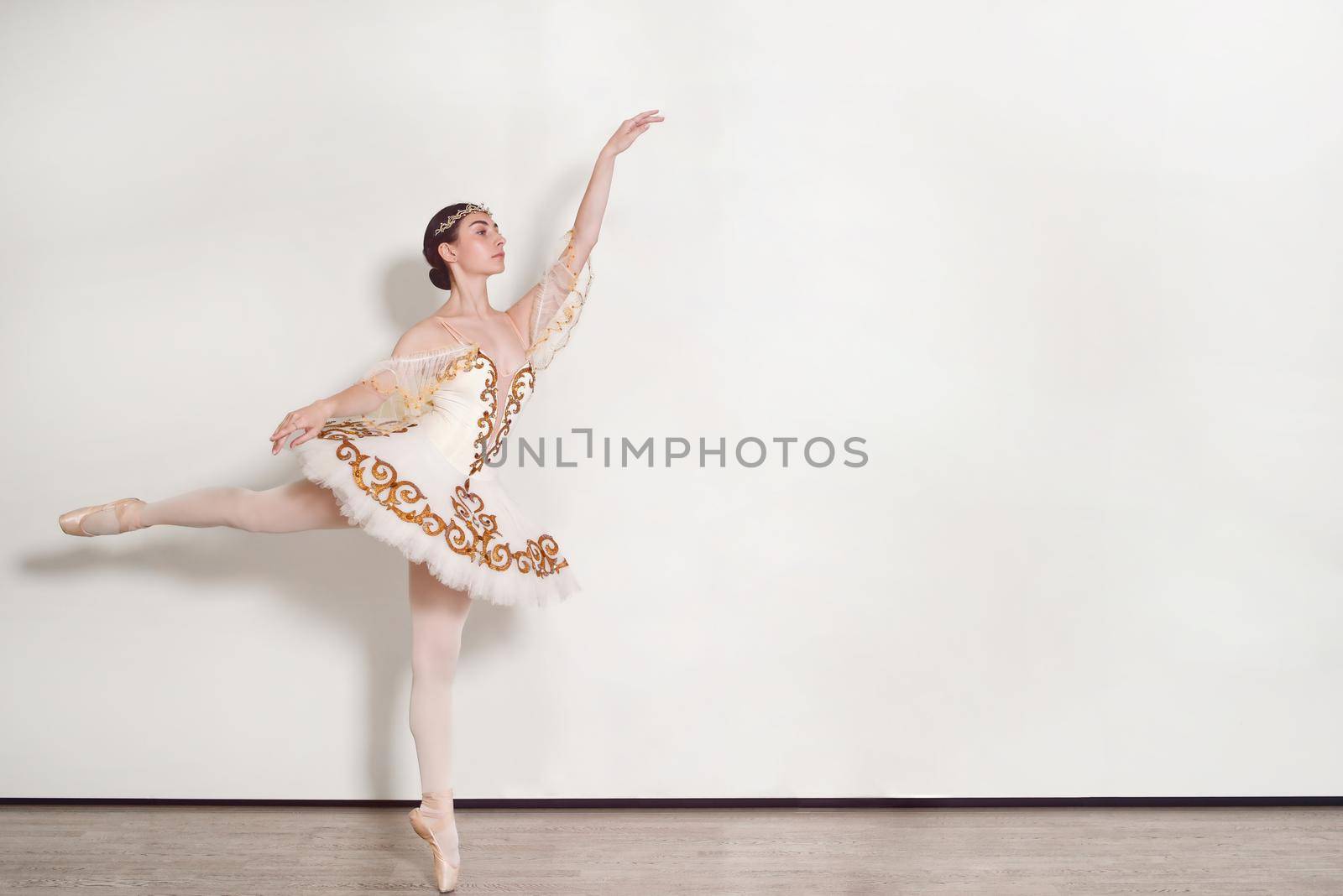 pretty ballerina performs ballet exercises in the studio against a white background