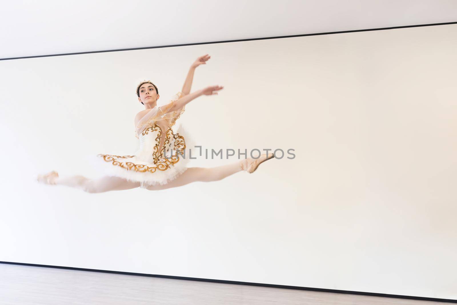 A young ballerina does ballet exercises in a jump in the ballet studio by Nickstock