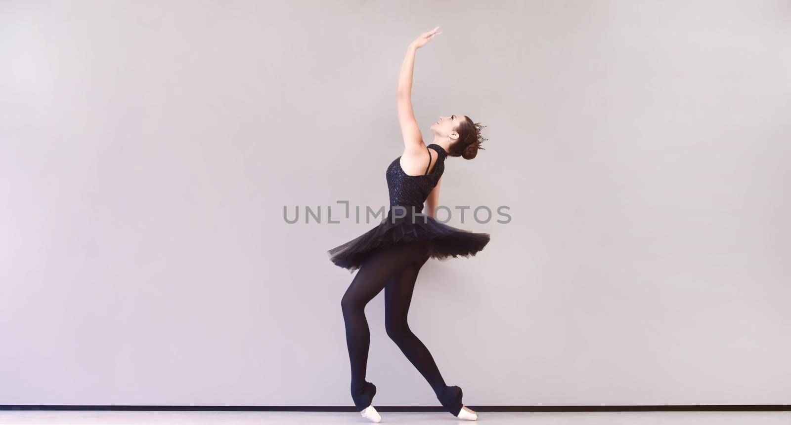 ballerina in black swan dress. Young ballet dancer practicing before performance in black tutu, classical dance studio, copy space by Nickstock
