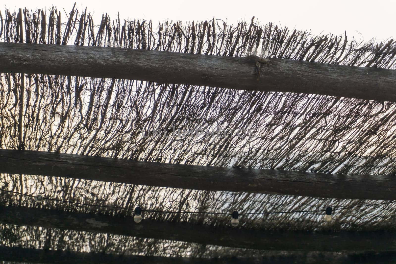 Wicker canopy from the sun with a garland of light bulbs against the sky