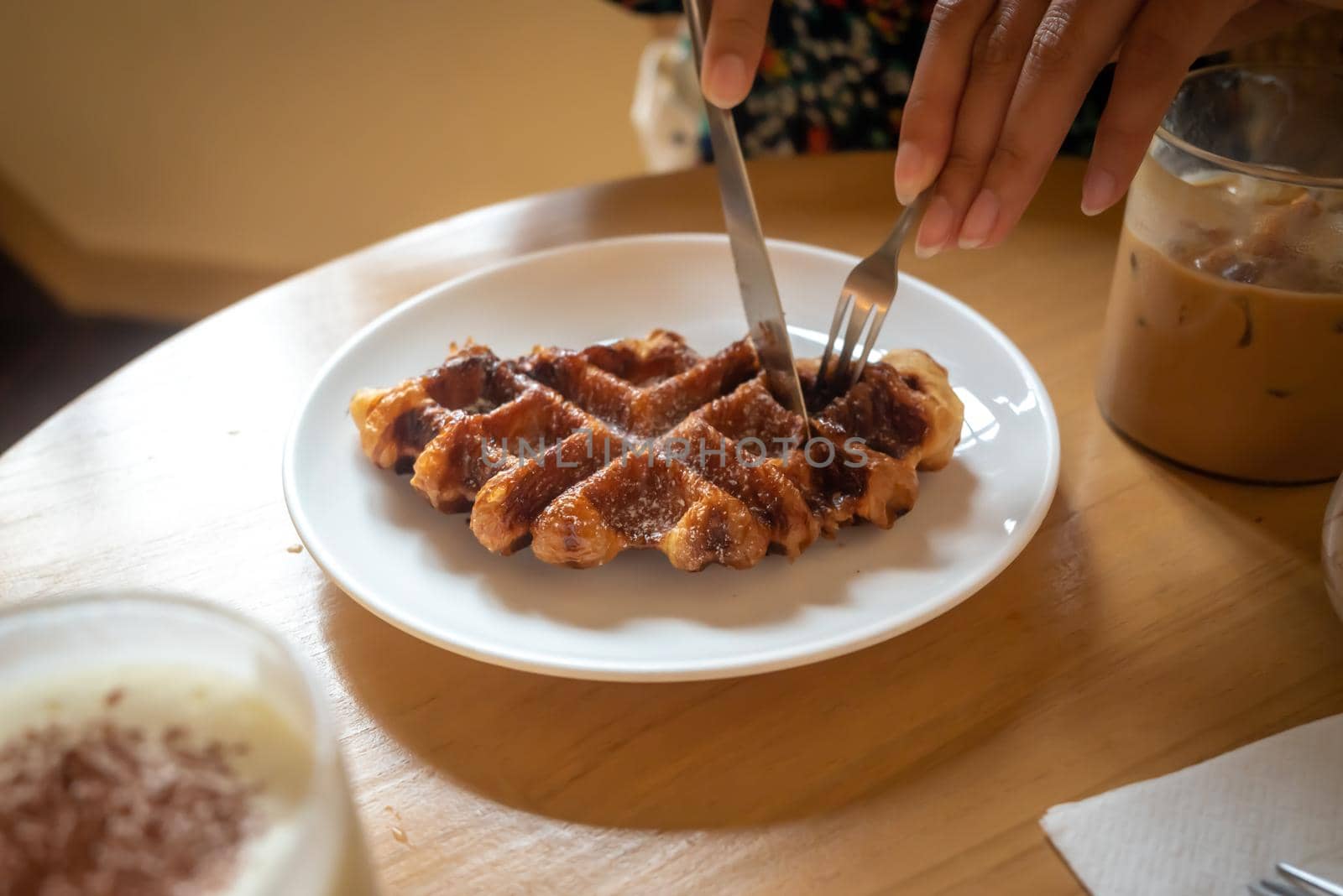 A Sunday morning meal in cafe, two cups of coffee, honey latte and Eispanner americano served with waffle on plate, decorated with with vase.